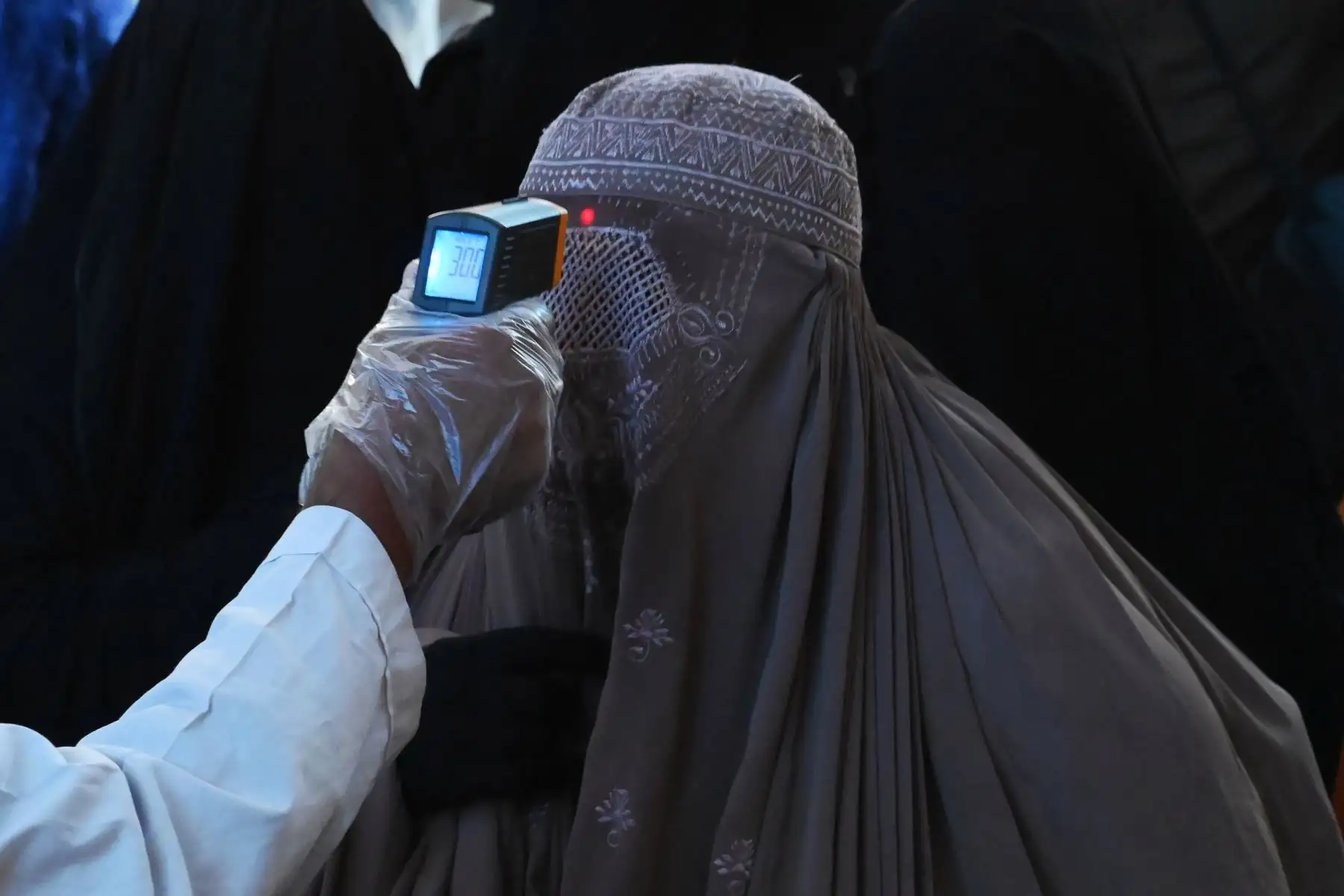 Un funcionario de salud verifica la temperatura corporal de una pasajera vestida de burka en medio de la preocupación por la propagación del nuevo coronavirus COVID-19 en la estación de tren de Lahore en Pakistán. Foto: AFP