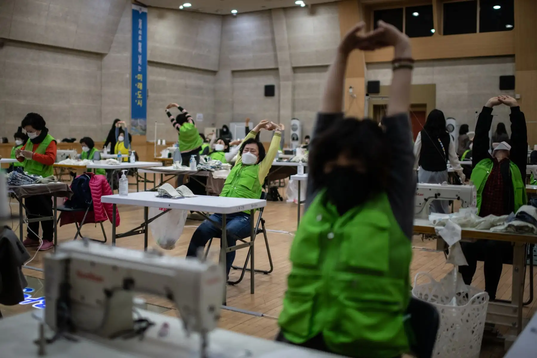 Los voluntarios realizan estiramientos de relajación mientras hacen máscaras faciales en una oficina de distrito en Seúl, Corea del Sur. Foto: AFP