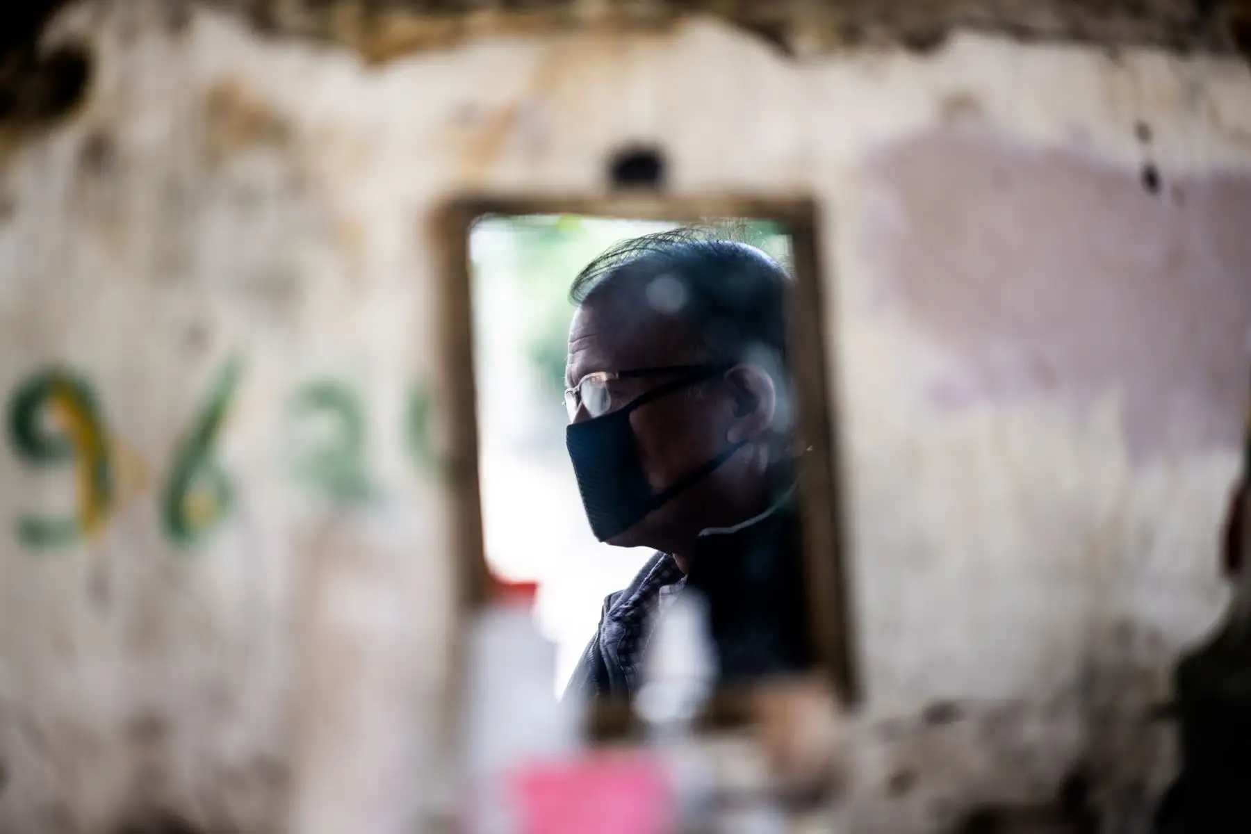 Un peluquero que usa una máscara facial como medida preventiva contra el coronavirus COVID-19 se refleja en un espejo mientras atiende a un cliente en su puesto de carretera en Nueva Delhi, India. Foto: AFP