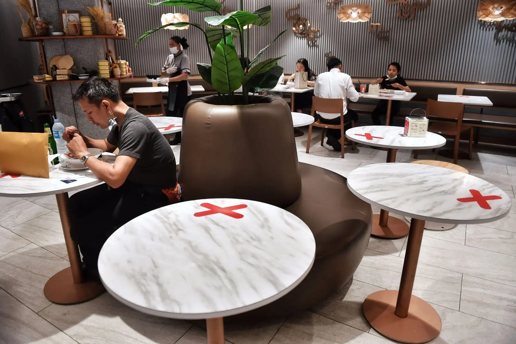 Los marcadores de distanciamiento social se muestran en las mesas del patio de comidas en un centro comercial en medio de la preocupación por la propagación del coronavirus COVID-19 en Bangkok, Tailandia. Foto: AFP