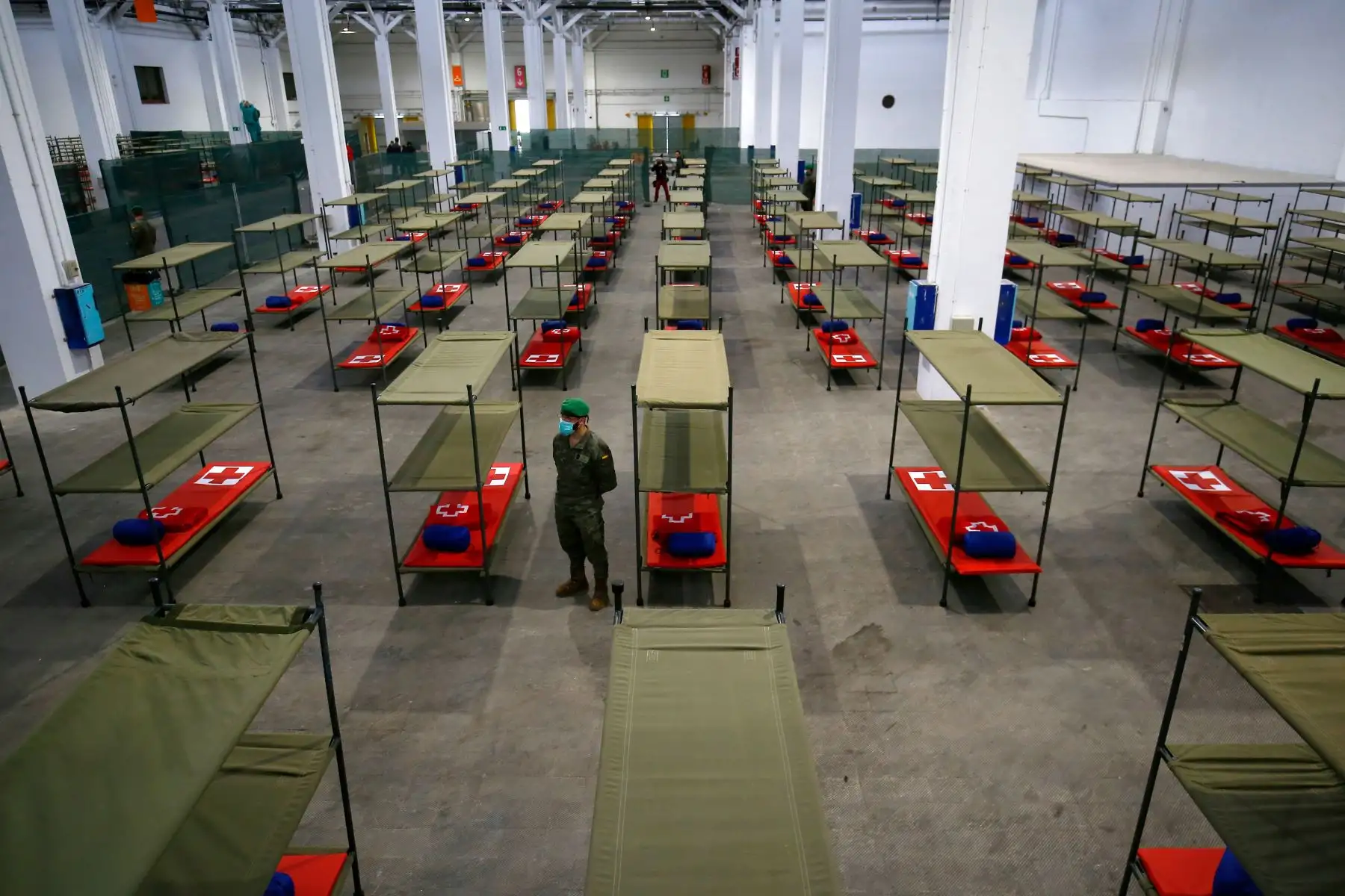 Un soldado español se para junto a las camas instaladas en un hospital temporal para personas vulnerables en el centro de Fira Barcelona. Foto: EFE
