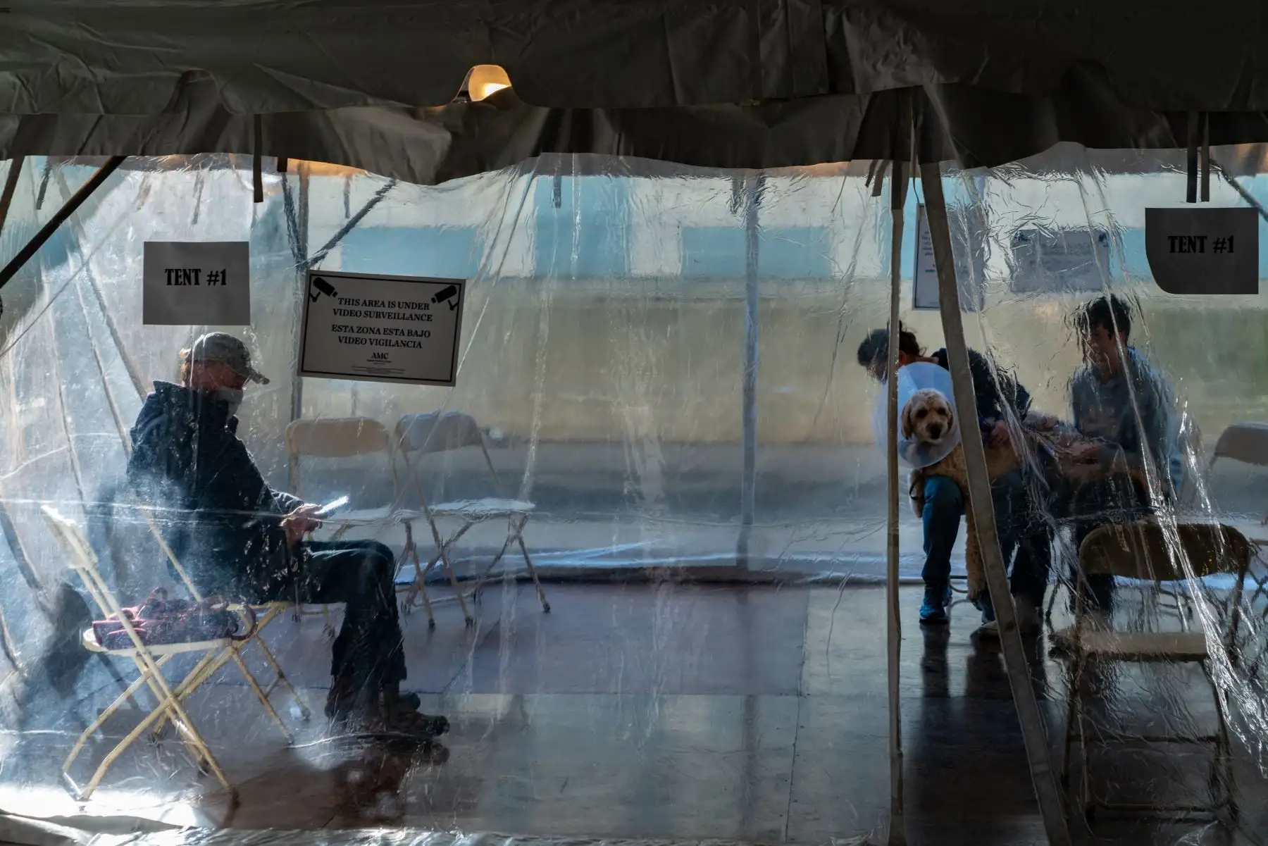 Los dueños de mascotas esperan en una carpa que se utiliza como sala de espera improvisada en el estacionamiento del Animal Medical Center mientras el hospital de animales toma precauciones contra COVID-19. AFP