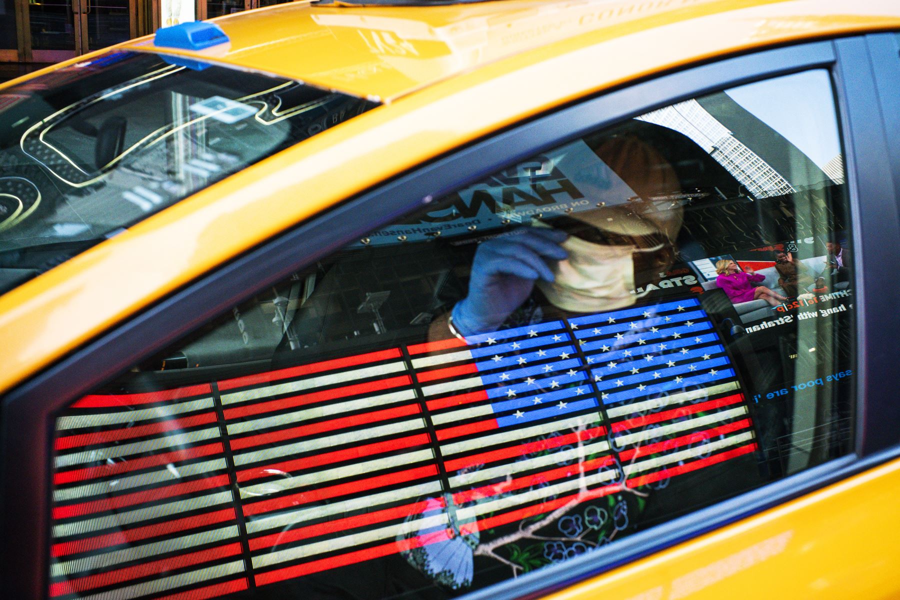 Un taxista usa una máscara facial y guantes mientras conduce por Times Square. AFP