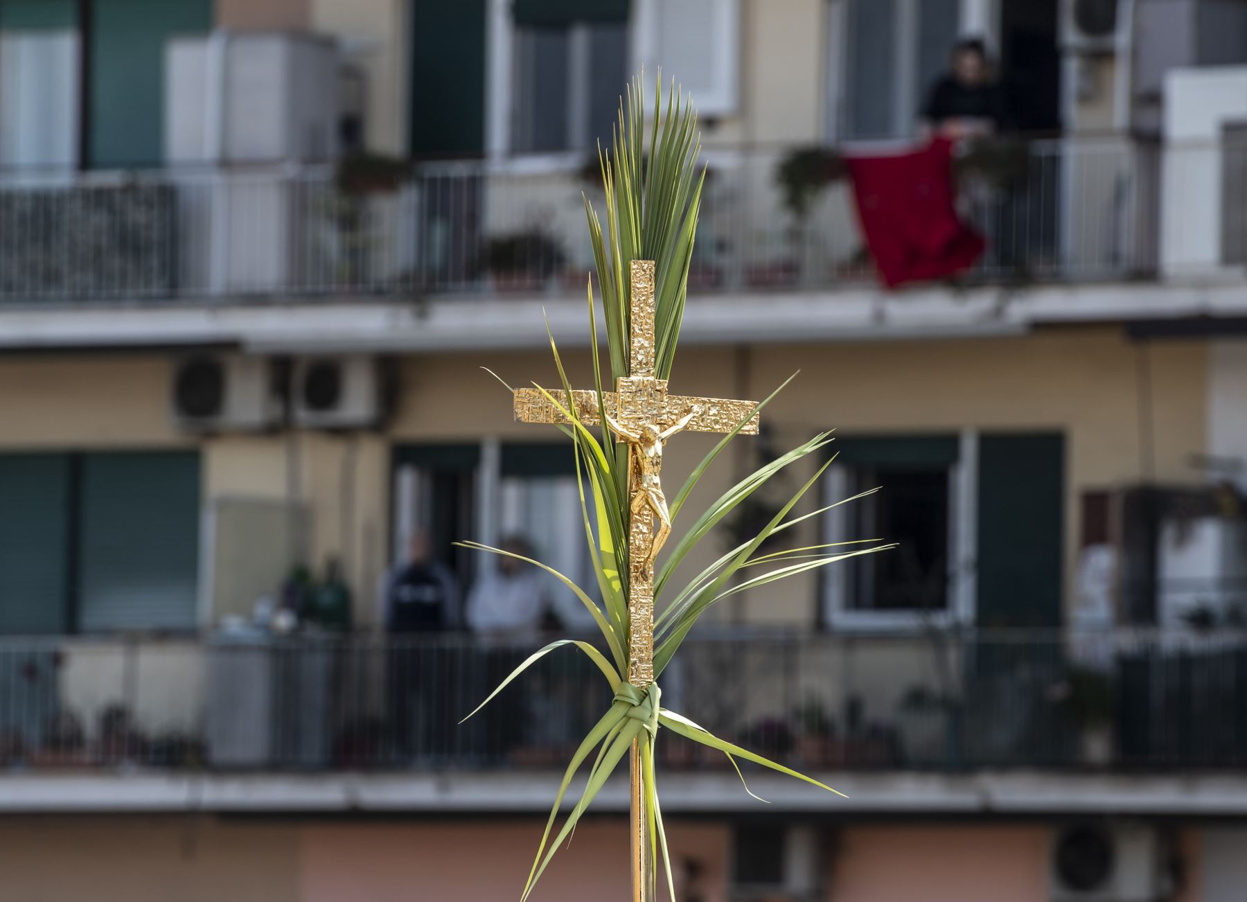 na vista muestra un crucifijo y una rama de palmera durante la misa del Domingo de Ramos celebrada para los residentes cercanos desde la azotea de la iglesia de San Gabriele dell