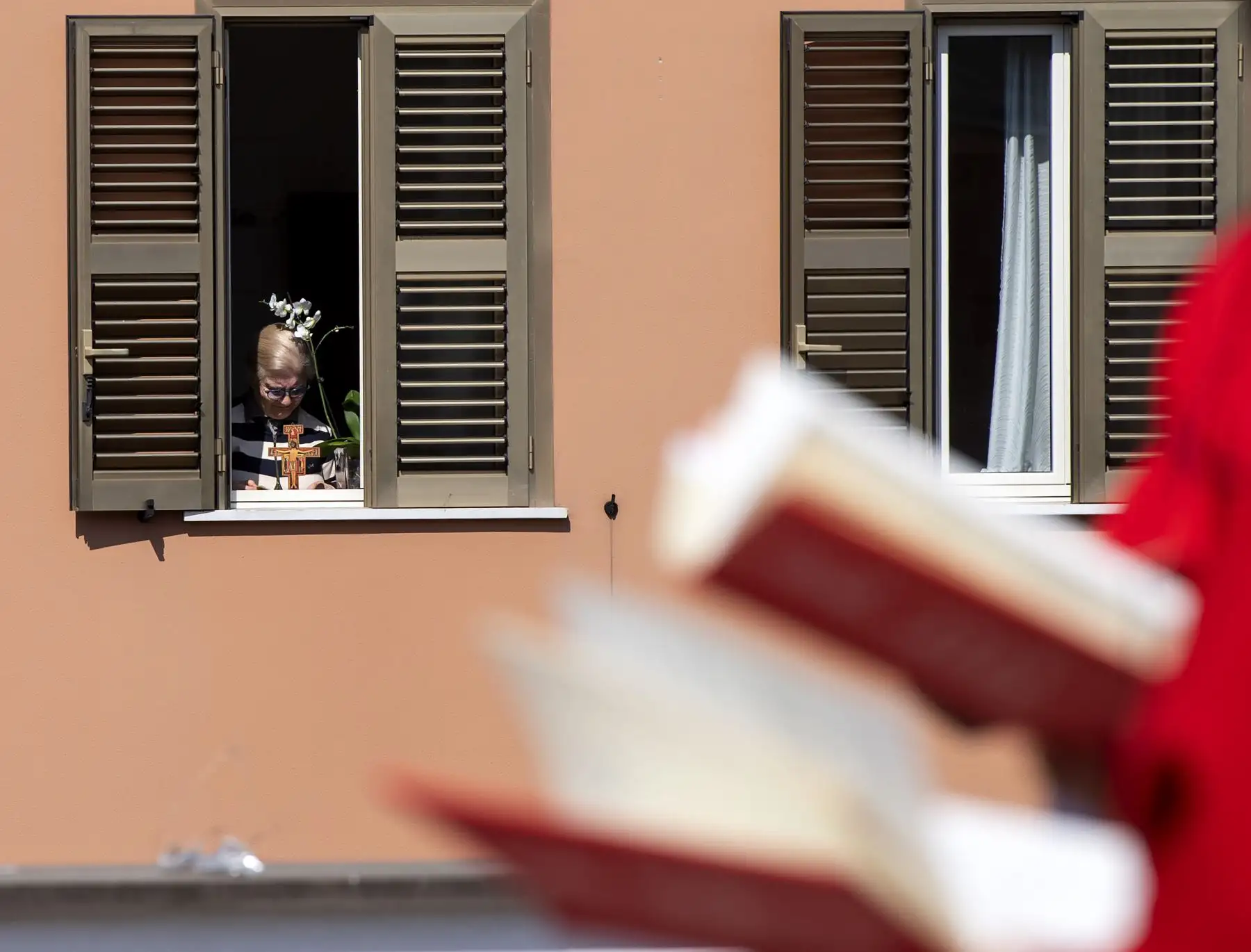 Una residente reflexiona desde su apartamento la misa del Domingo de Ramos celebrada en la azotea de la iglesia de San Gabriele dell