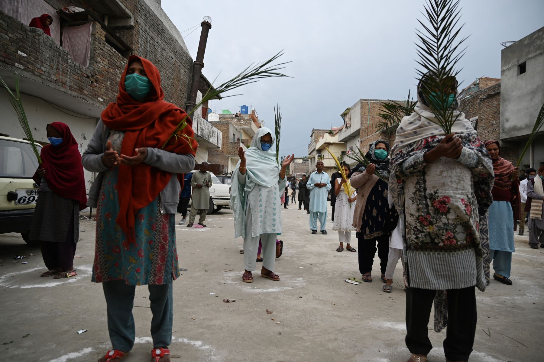 Los devotos cristianos se paran en círculos marcados en el suelo para mantener el distanciamiento social mientras sostienen ramas de palma para celebrar el Domingo de Ramos en Pakistan. Foto: AFP