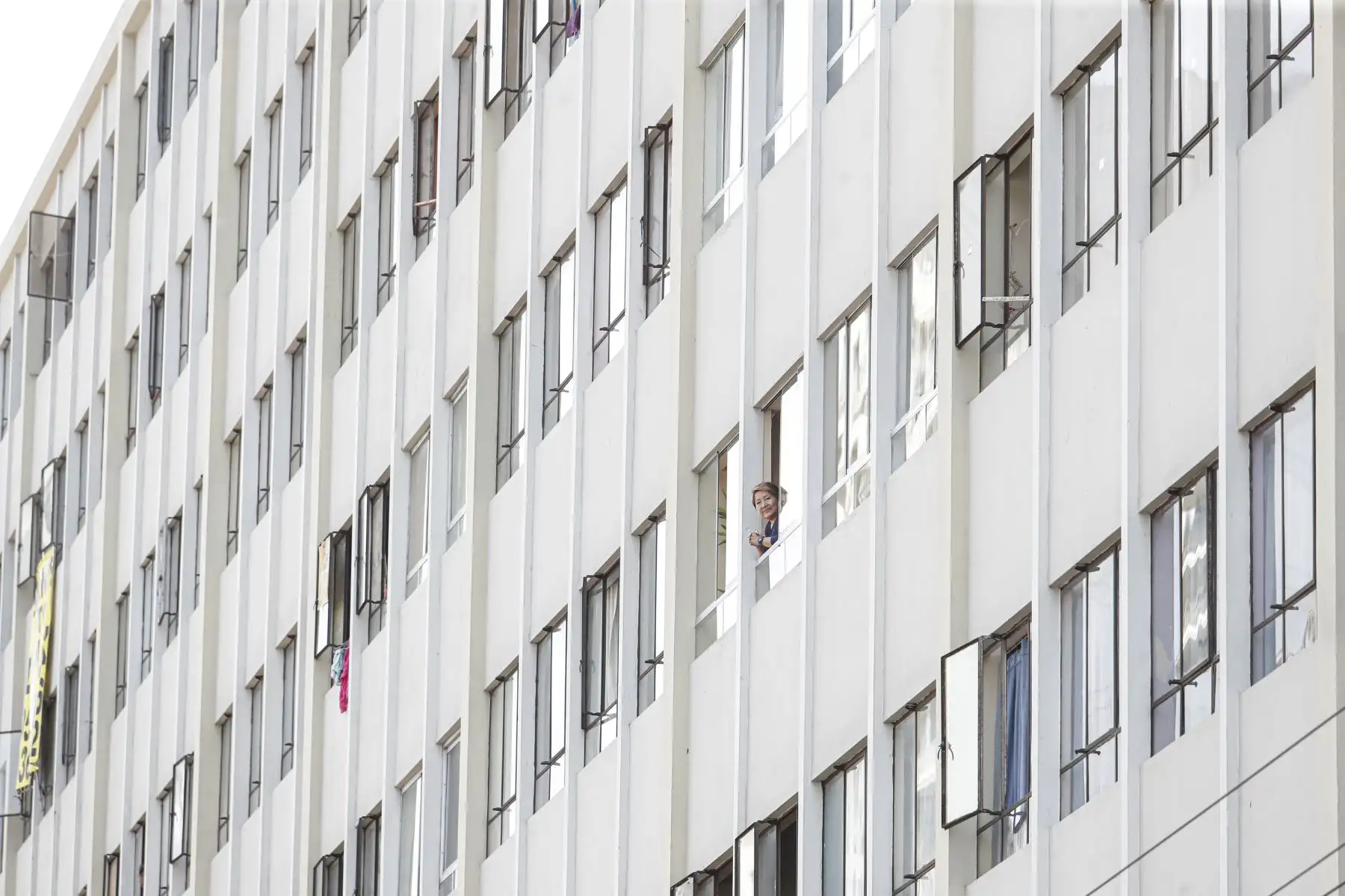 Una mujer observa desde la ventana de su vivienda ubicada la Av. Tacna del Centro de Lima. Foto: ANDINA/Renato Pajuelo