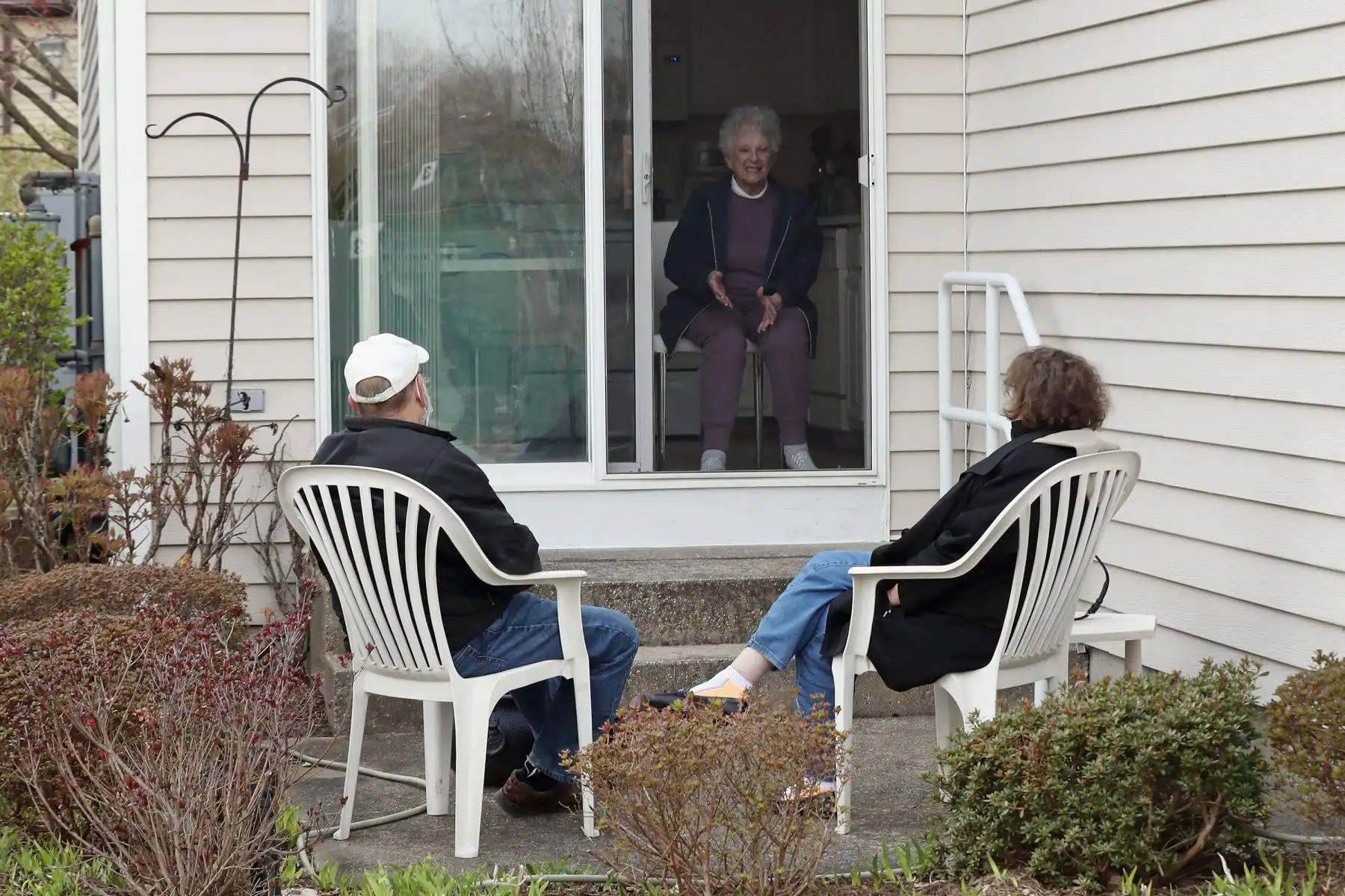 Un yerno y una hija visitan a su madre mientras practican el distanciamiento social en un complejo de viviendas para personas mayores en East Meadow, Nueva York. Foto: AFP
