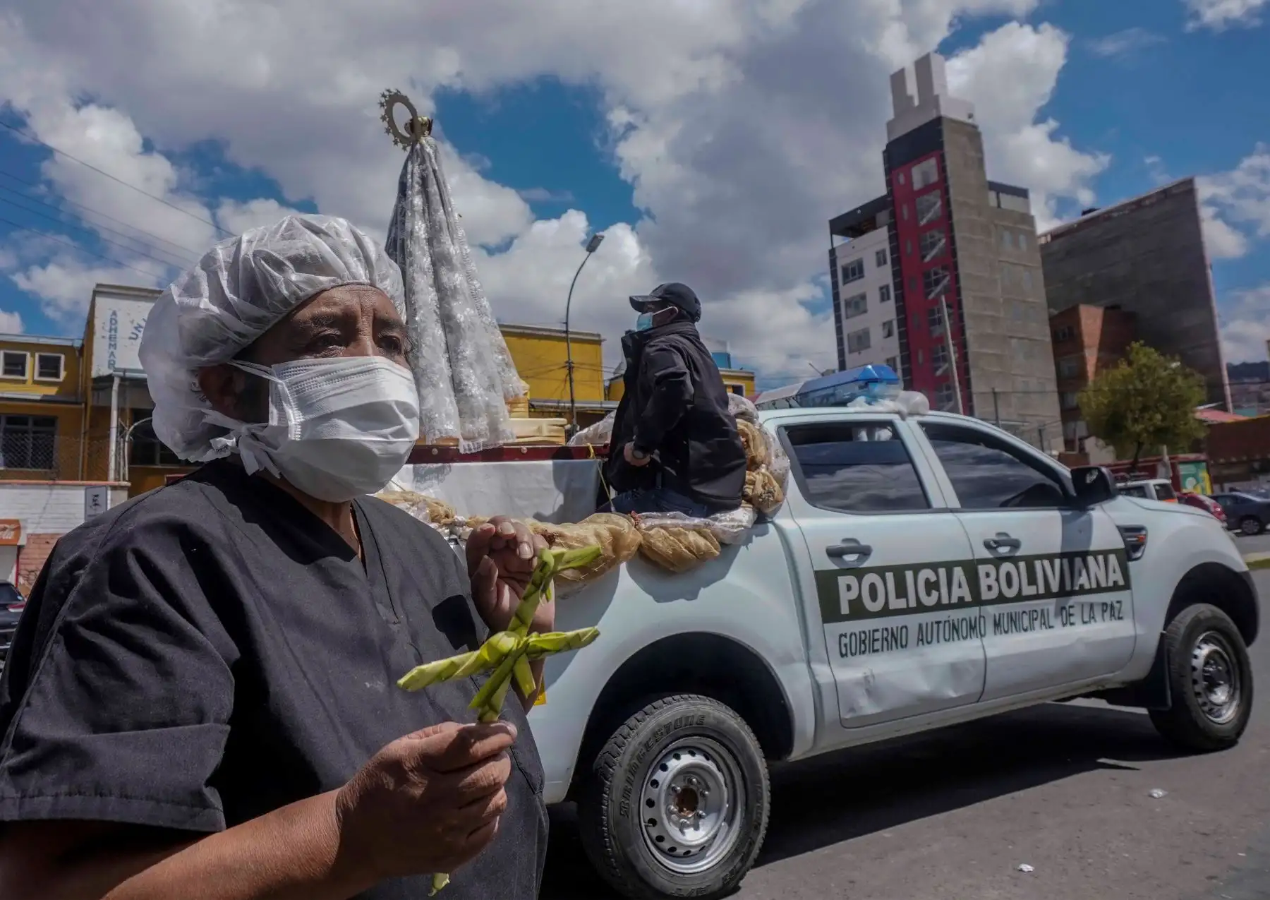 Trabajadora sanitaria boliviana sostiene una cruz hecha de palma durante visita de la imagen de la Virgen de Copacabana a un hospital en La Paz (Bolivia). Foto: EFE