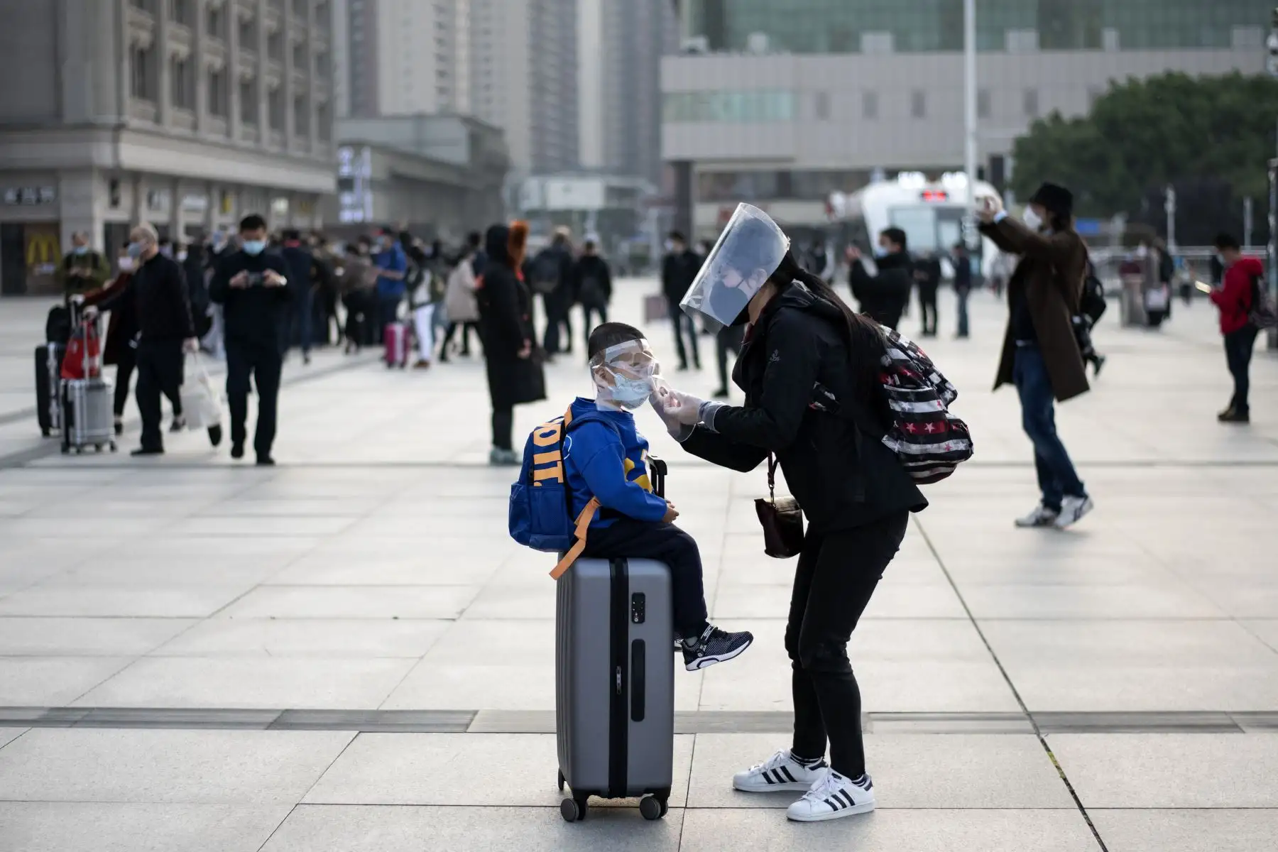Una mujer con una máscara facial ajusta la máscara de su hijo cuando llegan a la estación de tren de Hankou en Wuhan para tomar uno de los primeros trenes que salen de la ciudad.
Foto: AFP