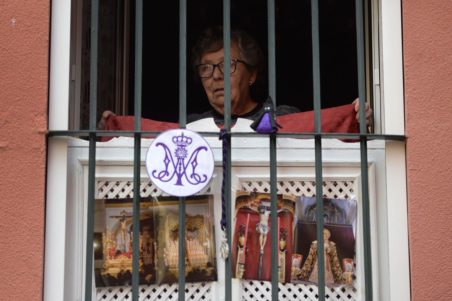 Una mujer decora su ventana con imágenes religiosas, en Sevilla, donde las procesiones de Semana Santa han sido canceladas debido a un cierre nacional para evitar la propagación deL coronavirus.
Foto: AFP