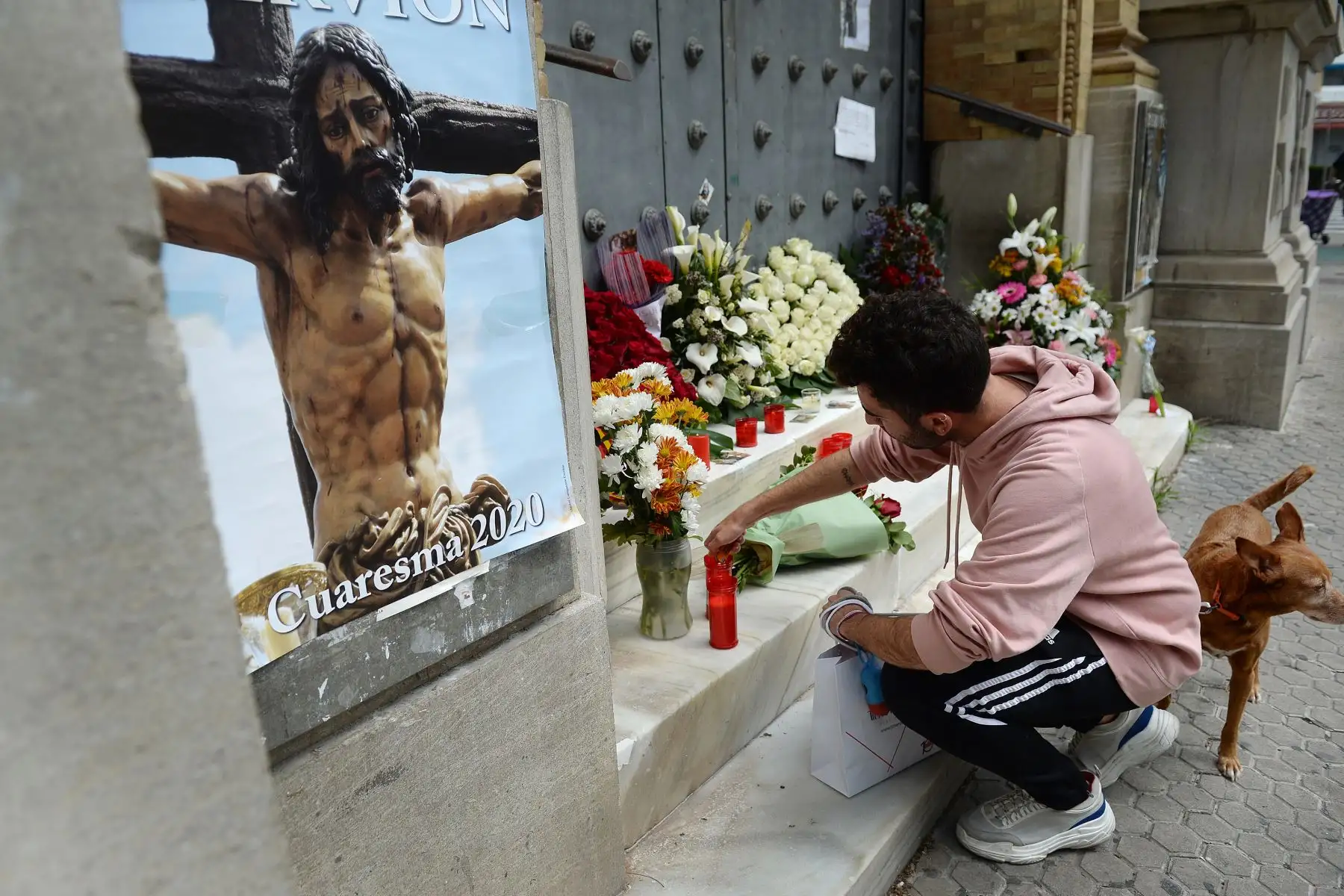 Un hombre enciende una vela, en la puerta de la iglesia Santisimo Cristo de la Sed (Cristo de la Sed) en Sevilla, adornada con flores dejadas por los fieles cuando las procesiones de Pascua fueron canceladas.
Foto: AFP