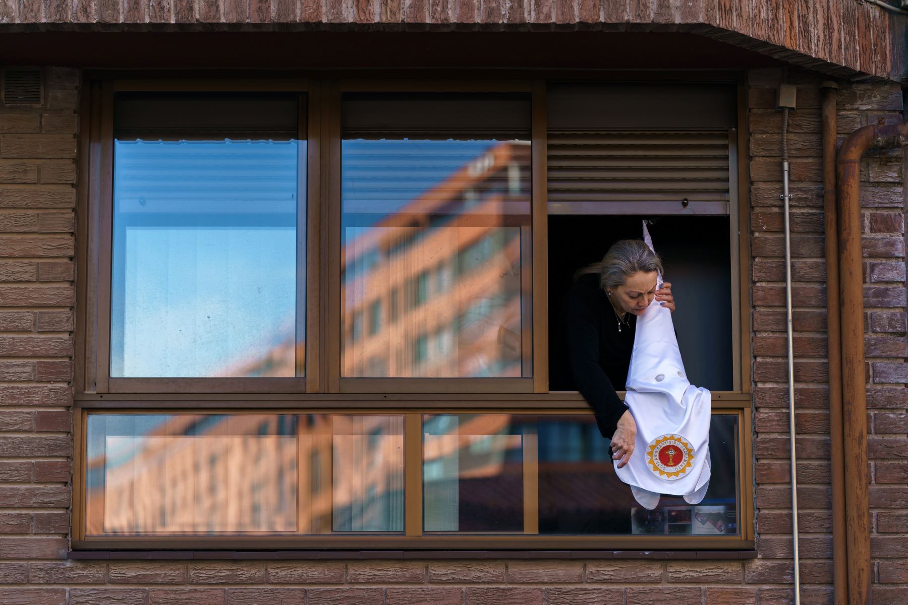 Una mujer coloca una capucha penitente de la hermandad "San Cosme y San Damián" en la ventana en Burgos, ya que las procesiones de Semana Santa fueron canceladas  para evitar la propagación de la enfermedad COVID-19.
Foto: AFP