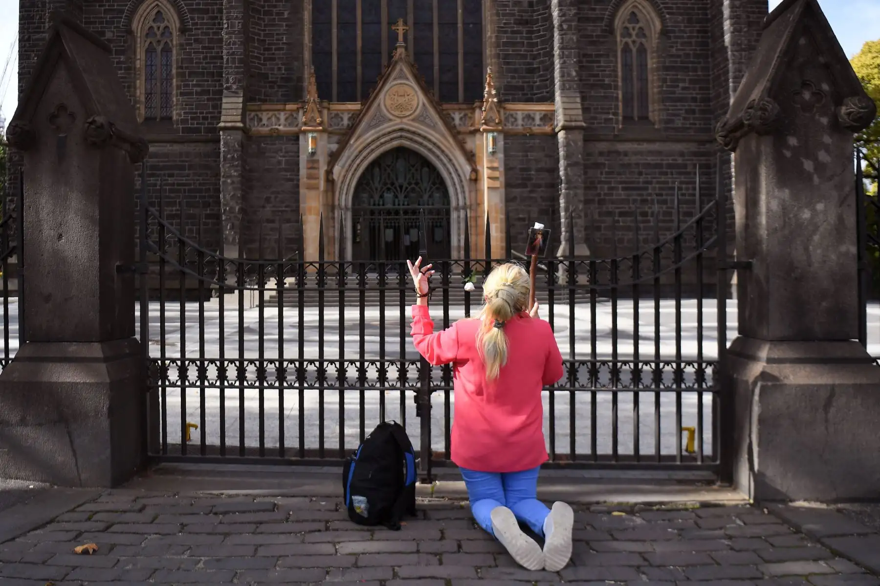 Una mujer reza afuera de la Catedral Católica de San Patricio el Viernes Santo en Melbourne, en  Australia. Foto: AFP