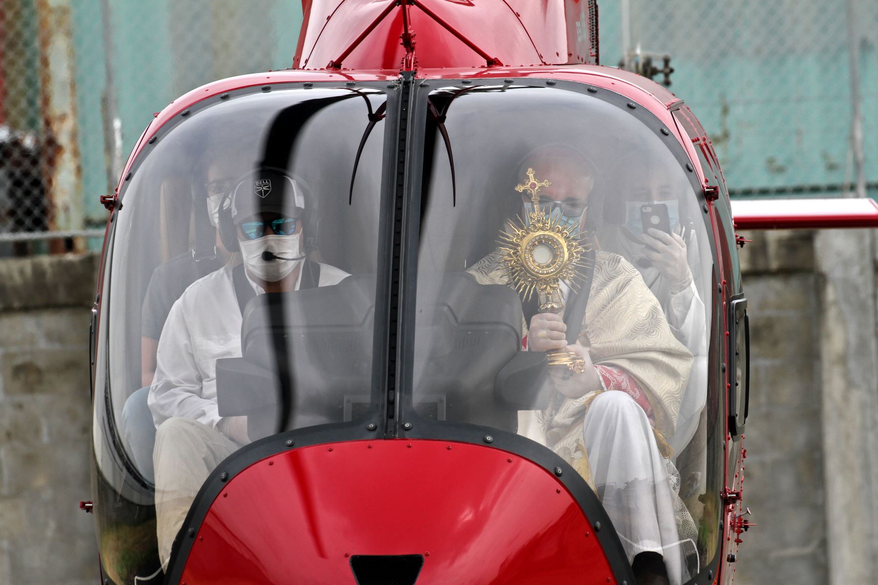 El obispo auxiliar de Guayaquil usa una máscara facial mientras da la bendición abordo de un helicóptero este Viernes Santo. Foto: AFP