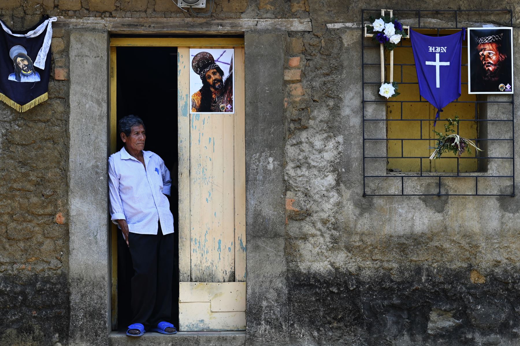 Un hombre permanece en la puerta de su casa, decorada para la Semana Santa, en la ciudad indígena de Izalco, en San Salvador. Foto: AFP