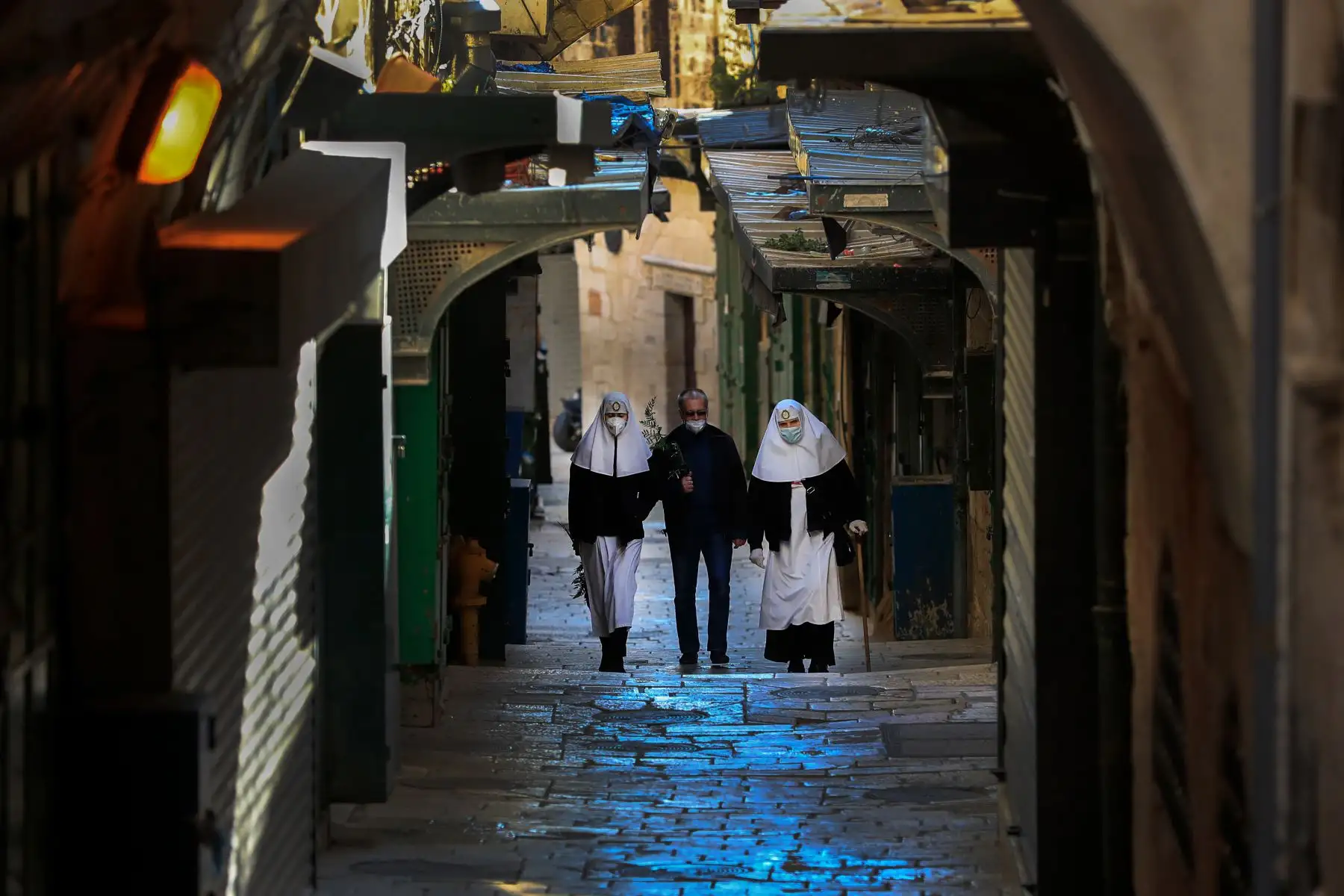 Dos monjas y un hombre, con máscaras protectoras, se dirigen a la Vía Dolorosa, vacía de fieles el domingo de Pascua, en medio de la nueva crisis pandémica de coronavirus, en la Ciudad Vieja de Jerusalén.
Foto: AFP