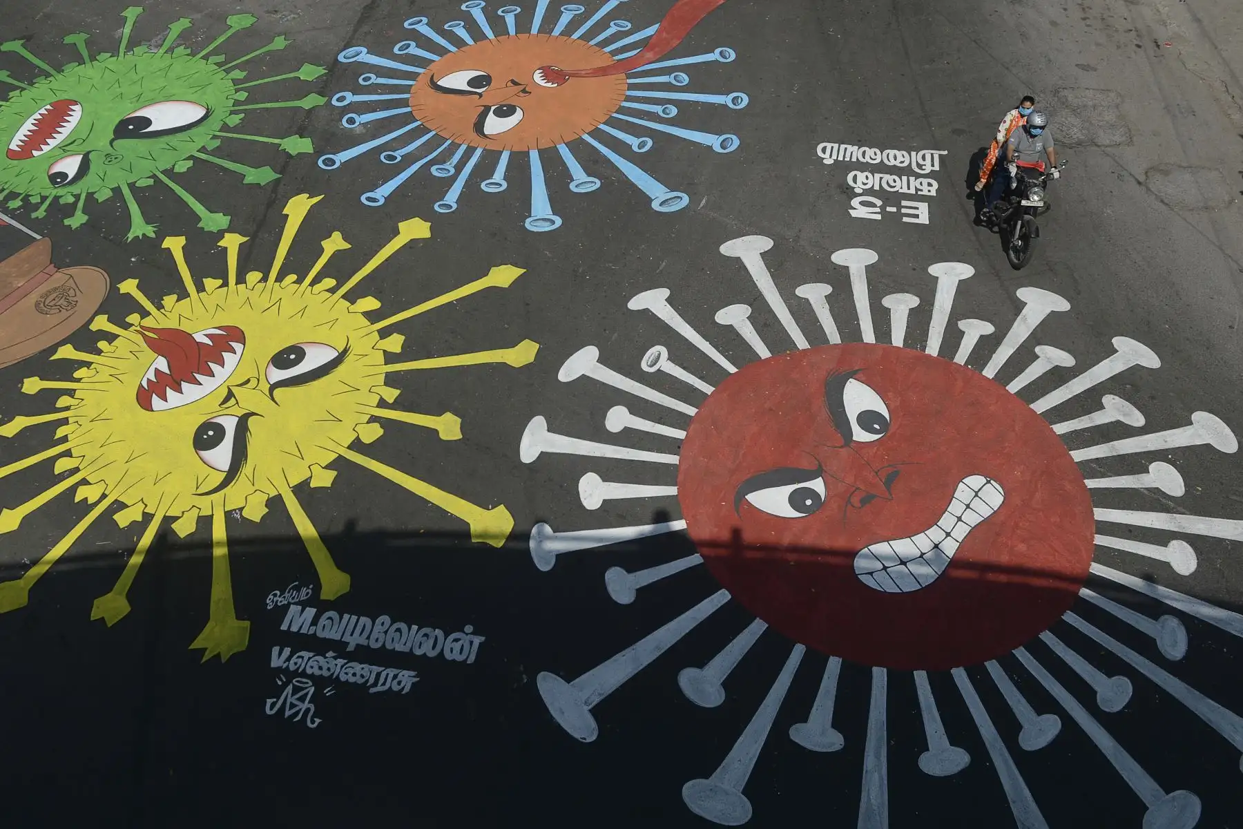 Un automovilista pasa junto a un graffiti pintado en una carretera para crear conciencia sobre el coronavirus COVID-19 durante un bloqueo nacional impuesto por el gobierno como medida preventiva contra el coronavirus COVID-19 en Chennai. AFP