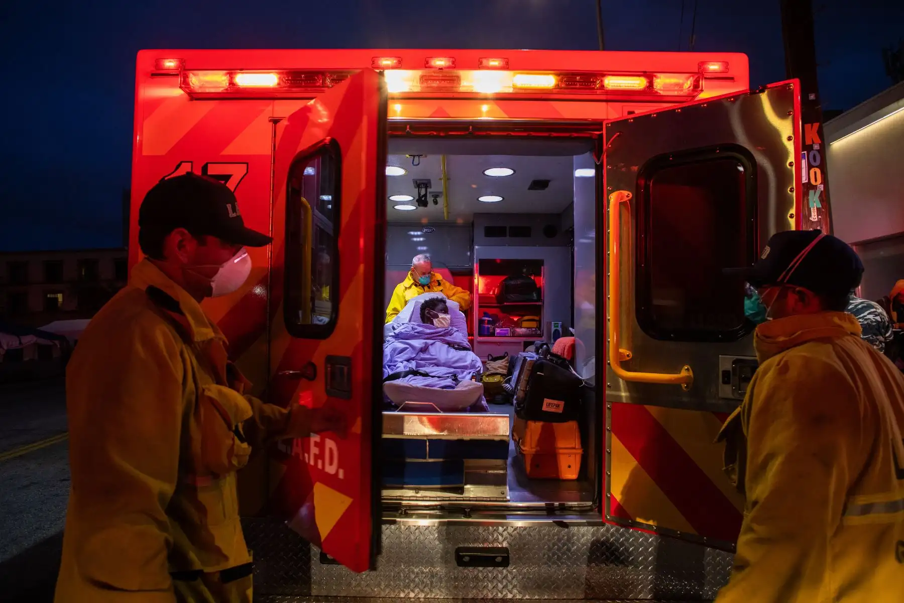 Los paramédicos de LAFD Station No9 usan una máscara facial como medida preventiva contra la propagación del nuevo coronavirus COVID-19 de una mujer sin hogar que tuvo convulsiones en la calle en Skid Row, antes de abordarla en la ambulancia para ir a un hospital en el centro de Los Ángeles, California. AFP