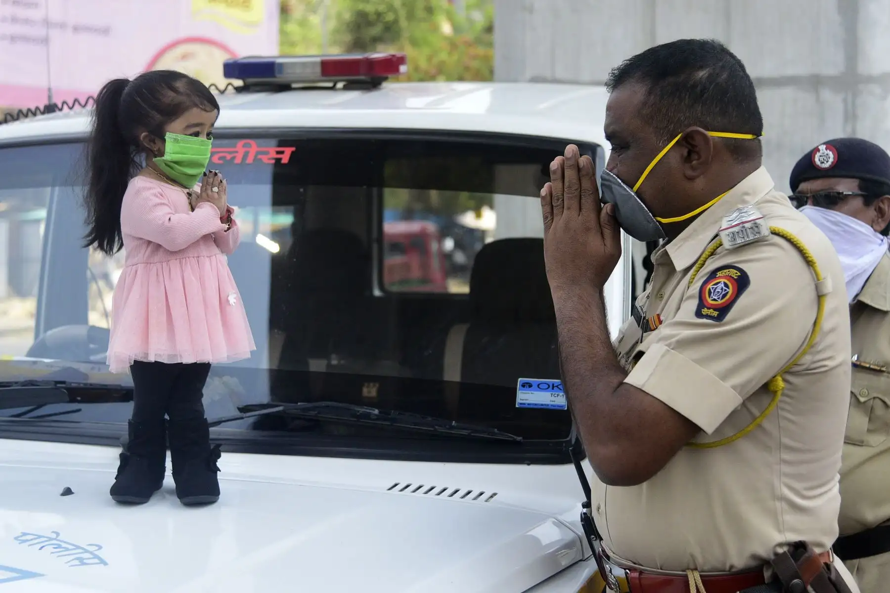 El poseedor del récord mundial Guinness de la mujer viva más pequeña del mundo, Jyoti Amge, saluda a un oficial de policía mientras pide a los ciudadanos que permanezcan dentro de sus hogares durante un cierre nacional impuesto por el gobierno como medida preventiva contra el COVID-19. AFP
