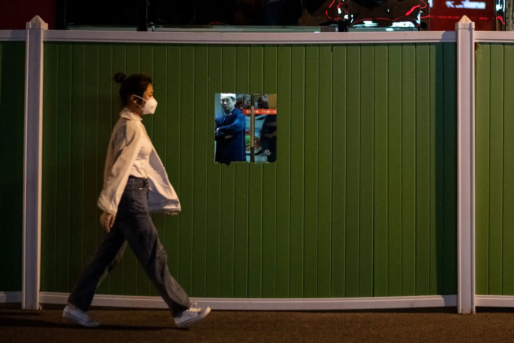 Una mujer con una máscara facial pasa junto a un complejo residencial con barricadas en Wuhan, en China.
Foto: AFP