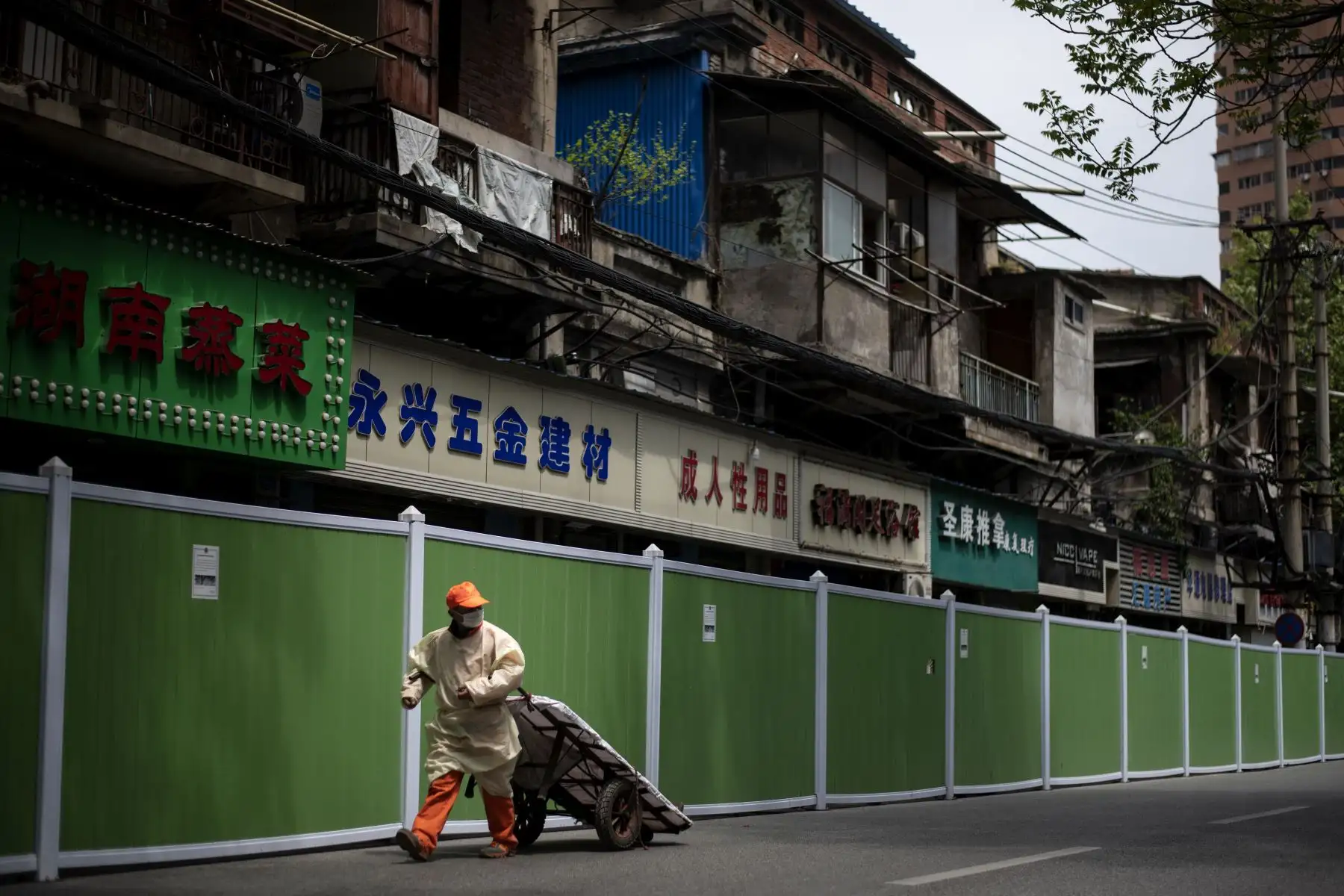 Un trabajador tira de un carro mientras camina en una barricada para mantener a las personas dentro y fuera de un complejo residencial en Wuhan.
Foto: AFP