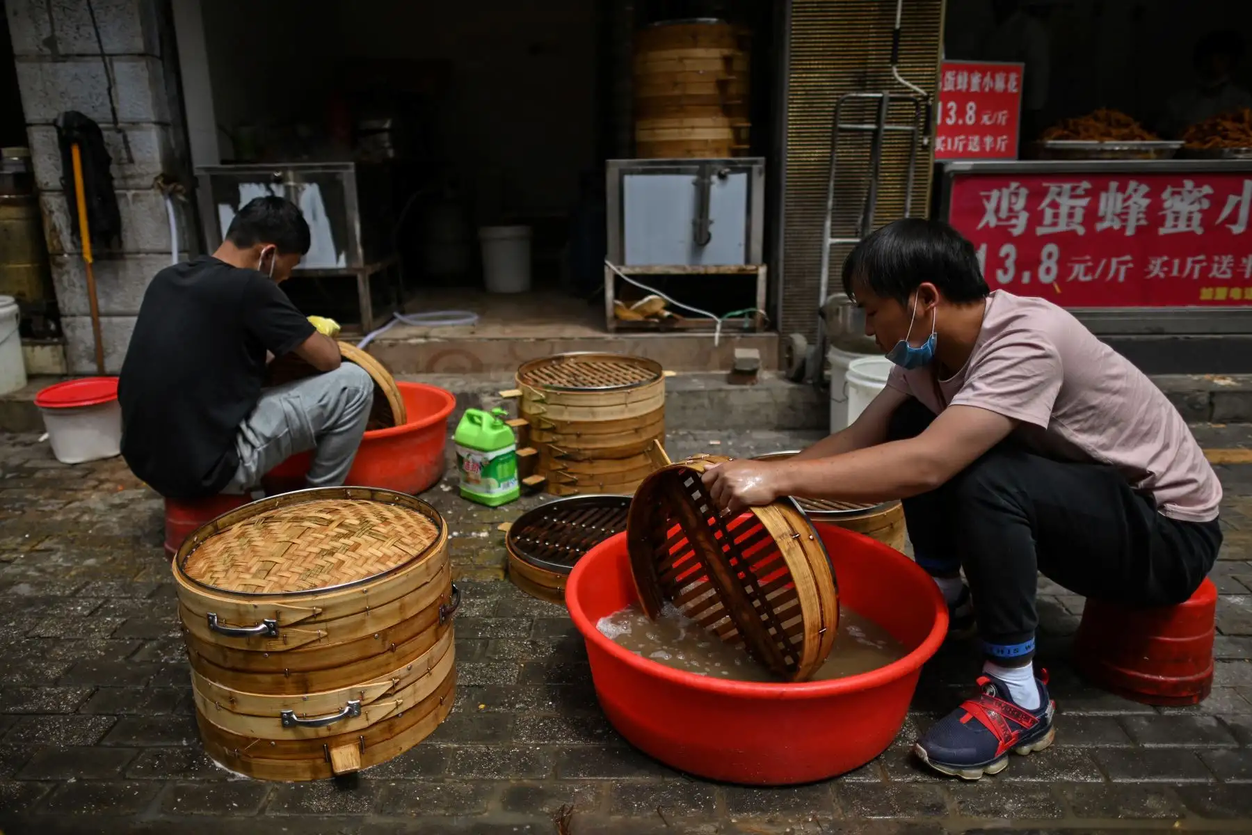Los hombres que llevan máscaras faciales lavan los utensilios de cocina en una calle de Wuhan, provincia central de Hubei, China.
Foto: AFP