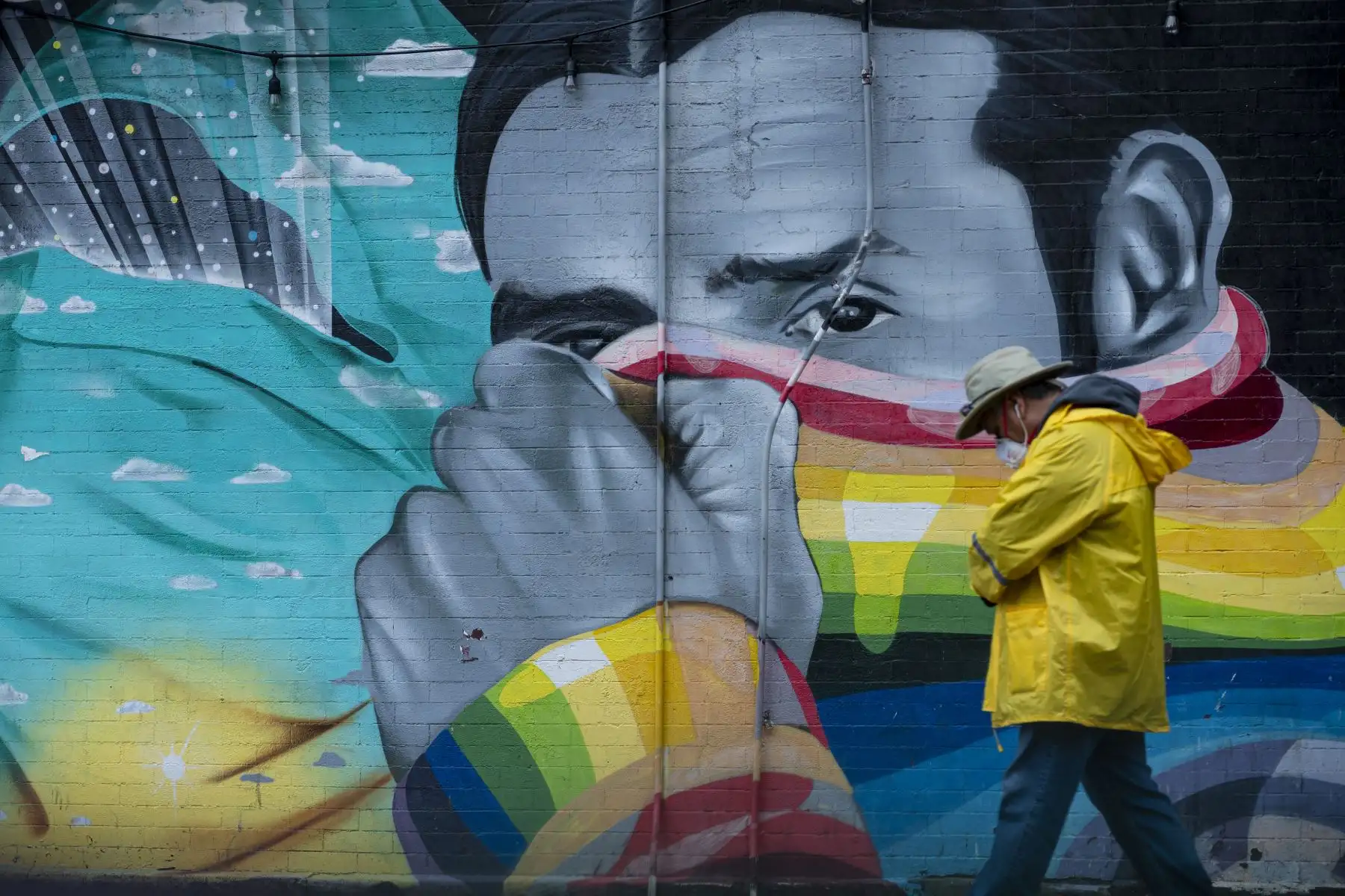 Un hombre con una máscara pasa un mural el de 2020 en la ciudad de Nueva York. Foto: AFP