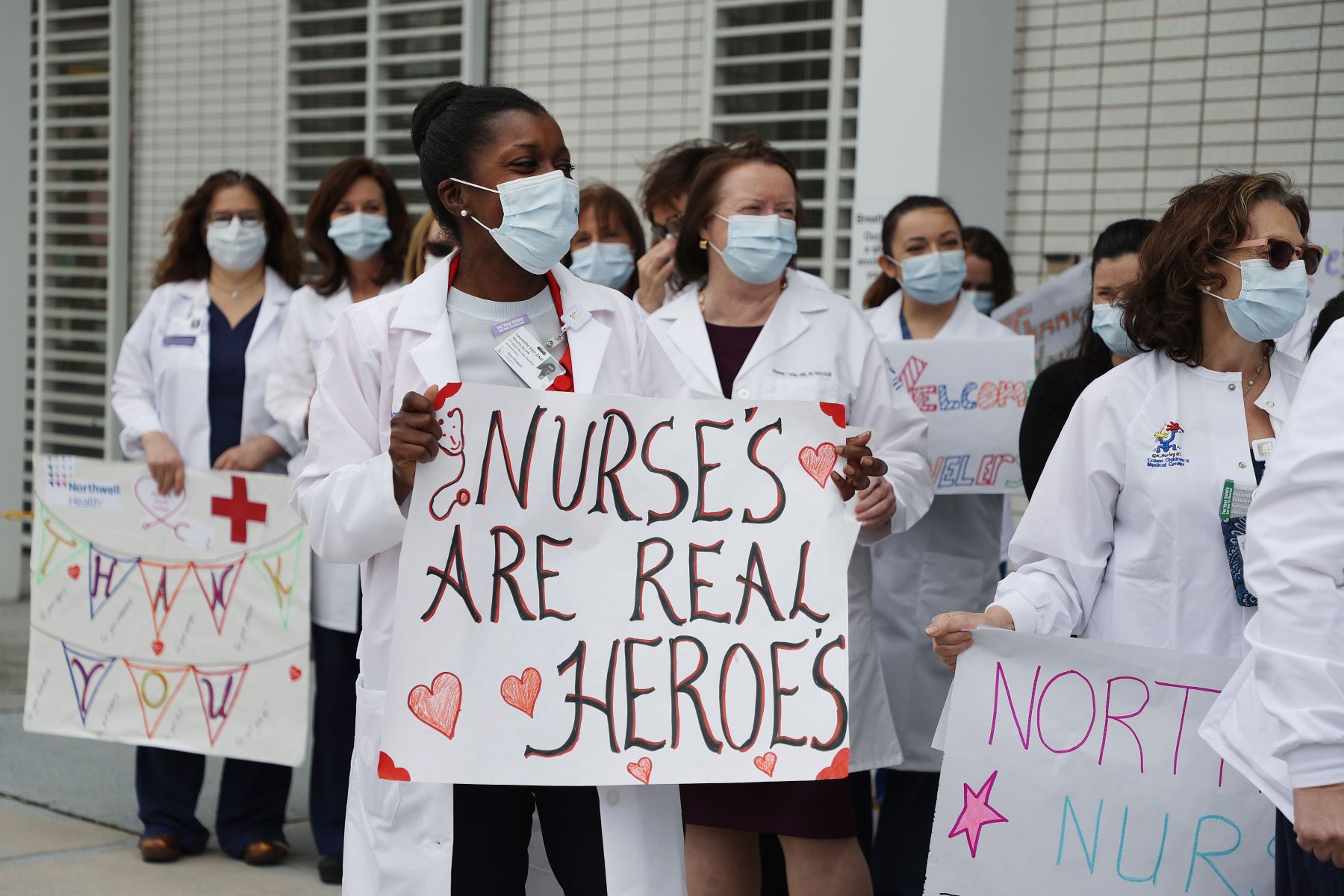 El personal de enfermería y los administradores sostienen carteles y esperan para dar la bienvenida y aplaudir a las enfermeras que llegan de todo el país para ayudar a tratar a los pacientes con coronavirus.
Foto: AFP