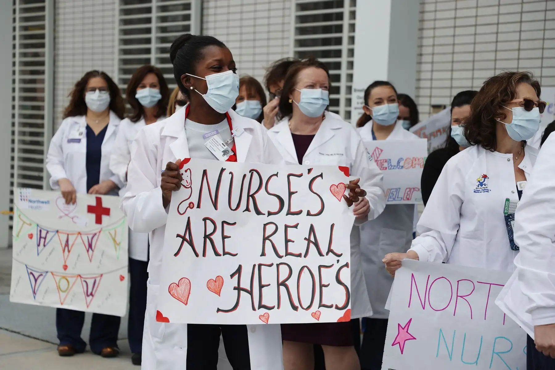 El personal de enfermería y los administradores sostienen carteles y esperan para dar la bienvenida y aplaudir a las enfermeras que llegan de todo el país para ayudar a tratar a los pacientes con coronavirus.
Foto: AFP