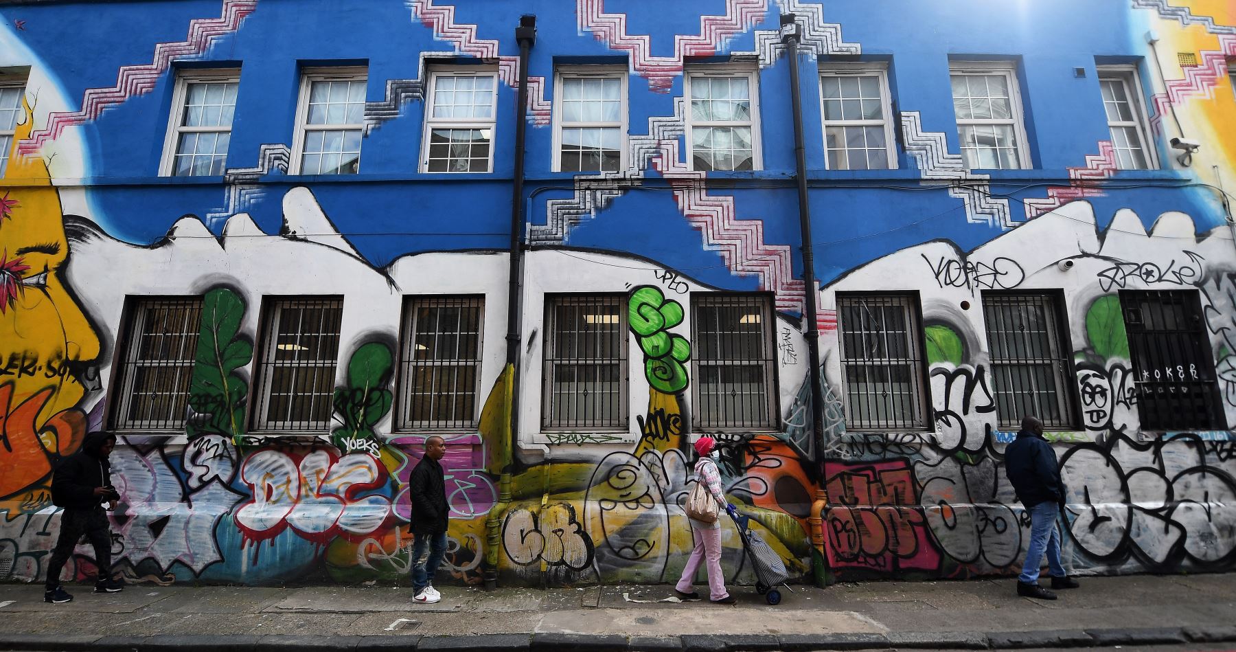 Las personas se adhieren al distanciamiento social mientras hacen cola frente a una oficina de correos en Peckham, Londres, Gran Bretaña. Foto: EFE