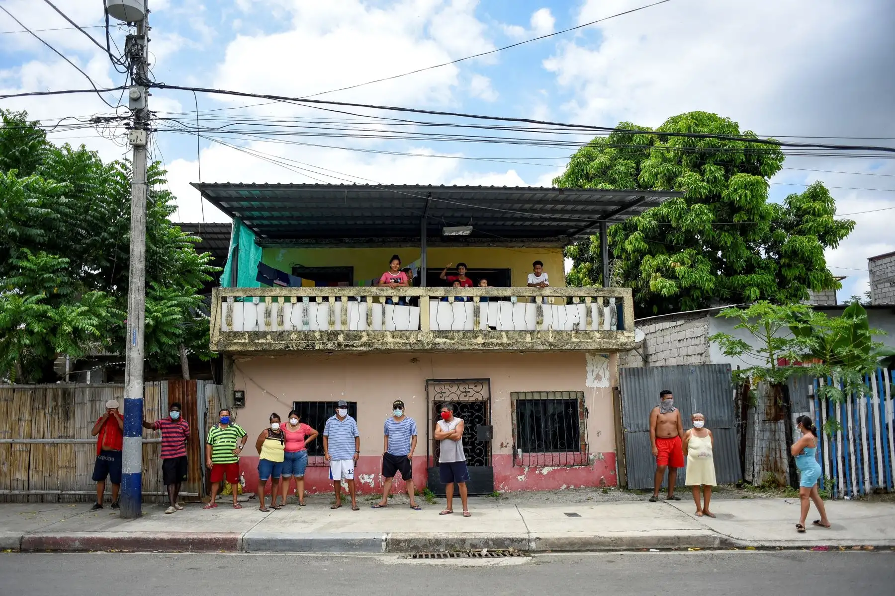 Vecinos de un fallecido en la ciudadela Bastión Popular en Guayaquil (Ecuador), observan hoy viernes a los policías ecuatorianos que forman parte del equipo de la Fuerza de Tarea Conjunta (FTC), para la recolección de los cadáveres en medio de la pandemia del COVID-19. Foto: EFE