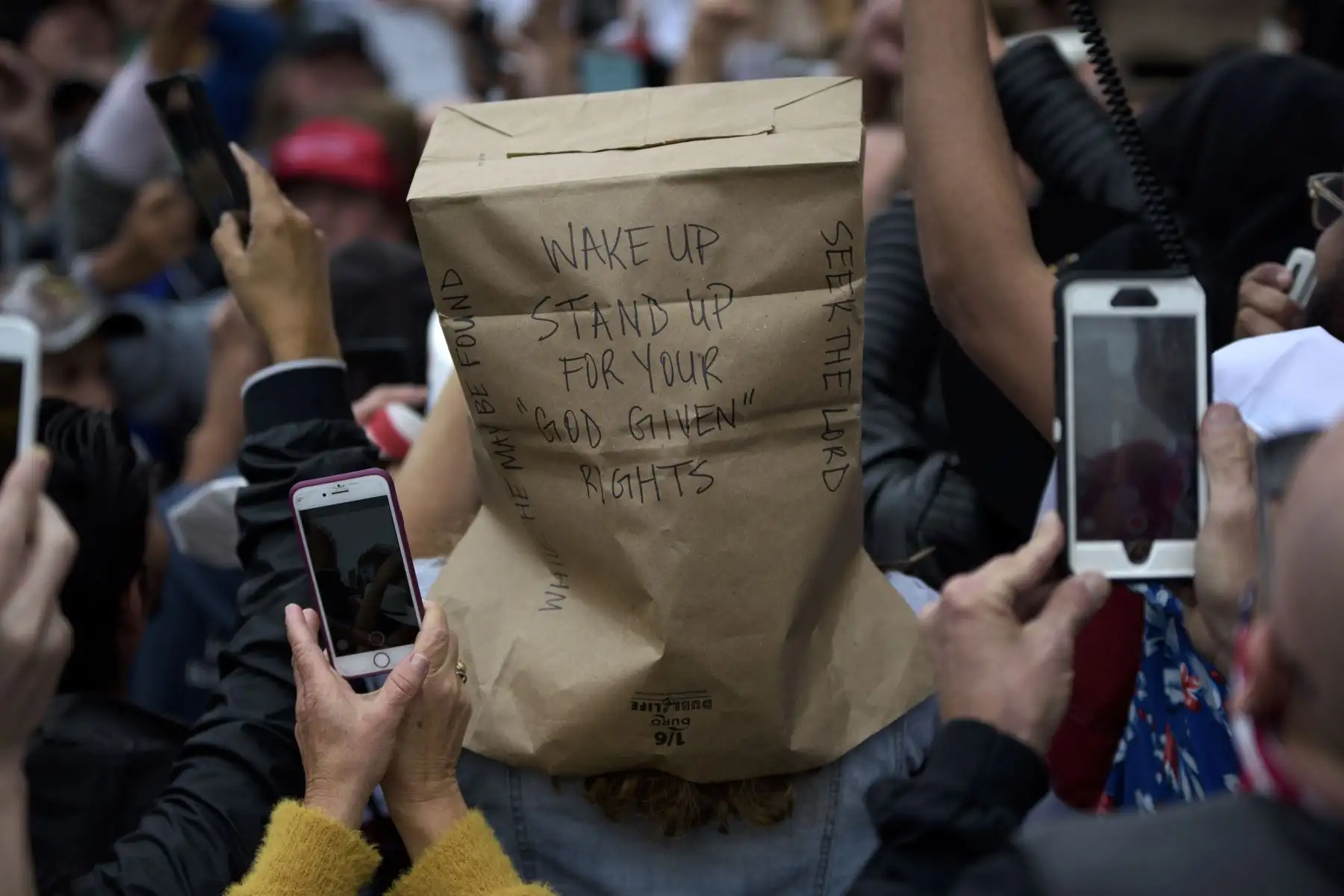 Un manifestante lleva una bolsa sobre su cabeza durante la manifestación "Reabrir América" el 18 de abril de 2020, en el Capitolio del Estado en Austin, Texas. Foto: AFP