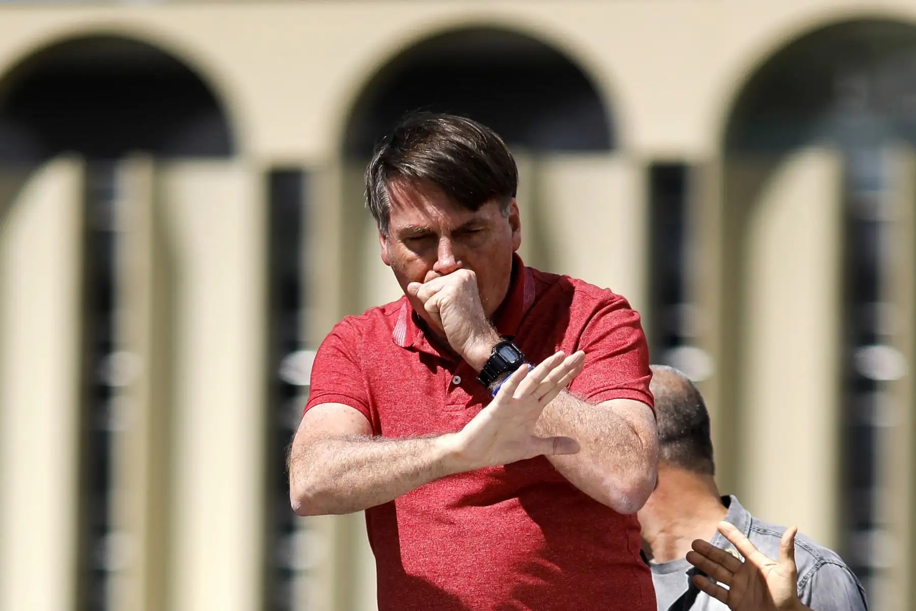 El presidente brasileño, Jair Bolsonaro, tose mientras habla después de unirse a sus seguidores que participaban en una caravana de automóviles para protestar contra las medidas de cuarentena y distanciamiento social para combatir el nuevo brote de coronavirus en Brasilia. Foto: AFP