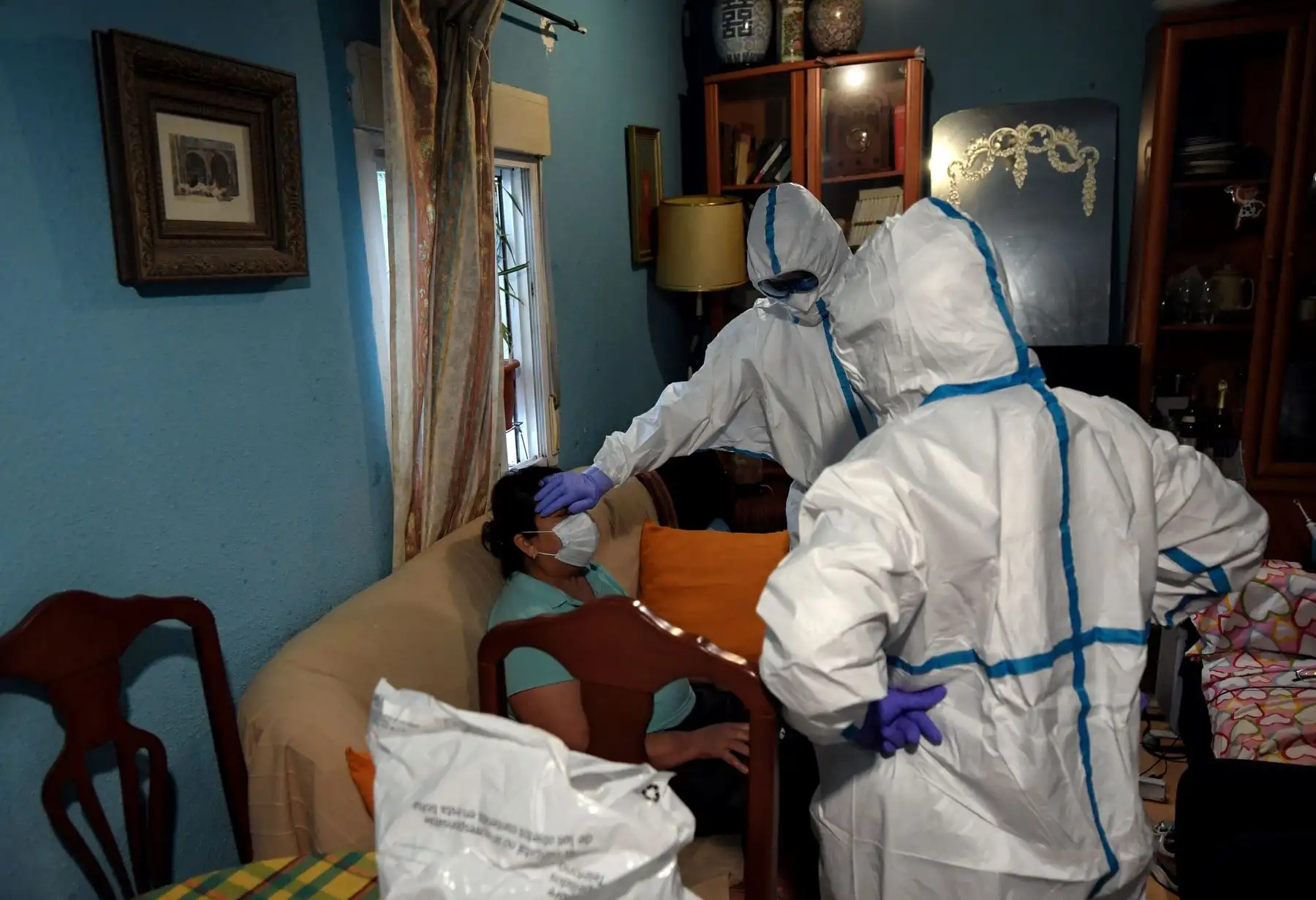 Trabajadores sanitarios de la unidad UVI-6 de los Servicios de Emergencias Médicas de Madrid (SUMMA 112), con trajes protectores, examinan a un presunto paciente con COVID-19 en su casa de Madrid. Foto: AFP