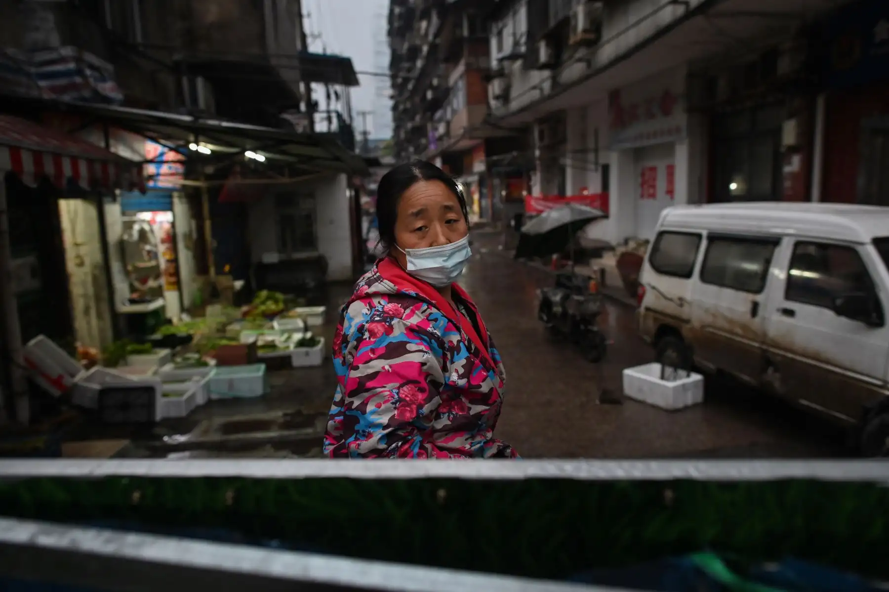 Una mujer, que usa una máscara facial como medida preventiva contra la propagación del nuevo coronavirus COVID-19, se encuentra en un acceso a un vecindario cerrado por barreras en Wuhan, la provincia central de Hubei de China. Foto: AFP