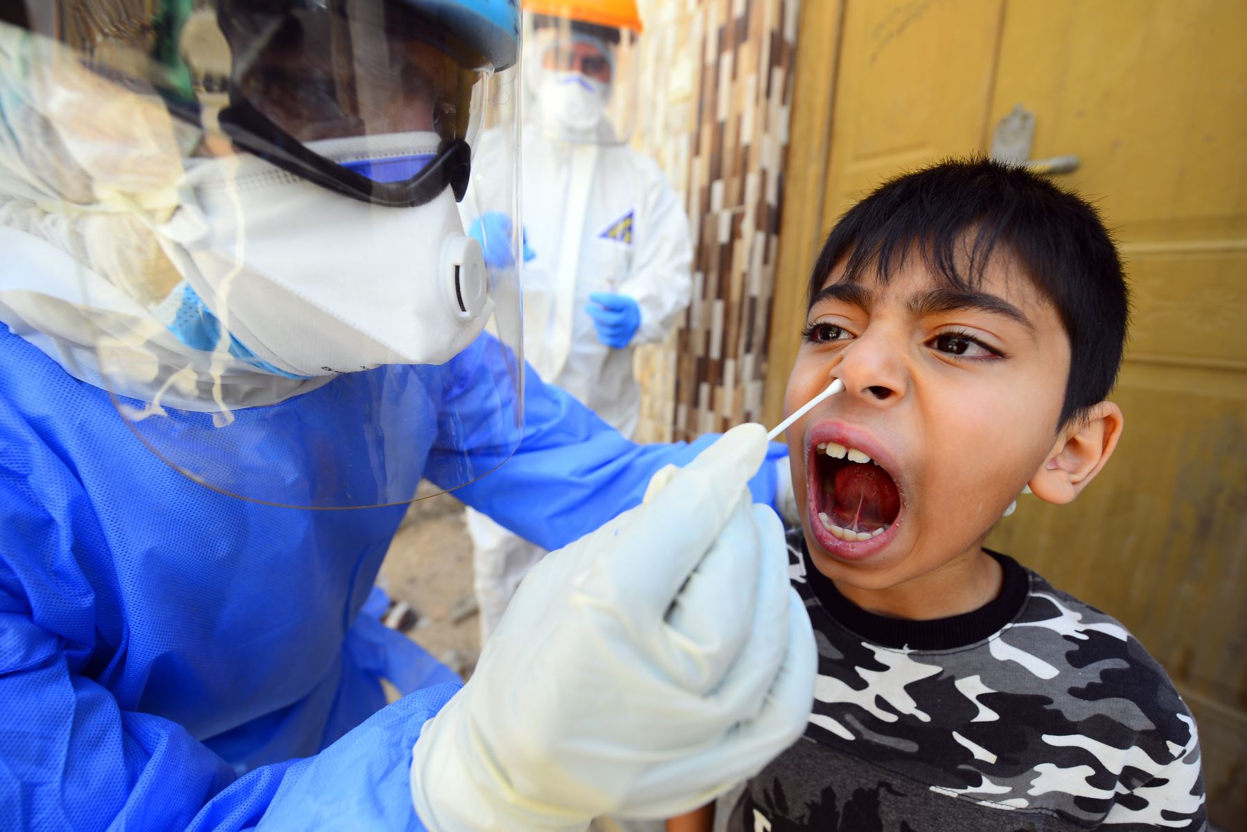 Un médico iraquí toma un hisopo nasal de un niño en la ciudad santuario central de Iraq de Najaf el 20 de abril de 2020, durante el cierre nacional para detener la propagación del nuevo coronavirus. Foto: AFP