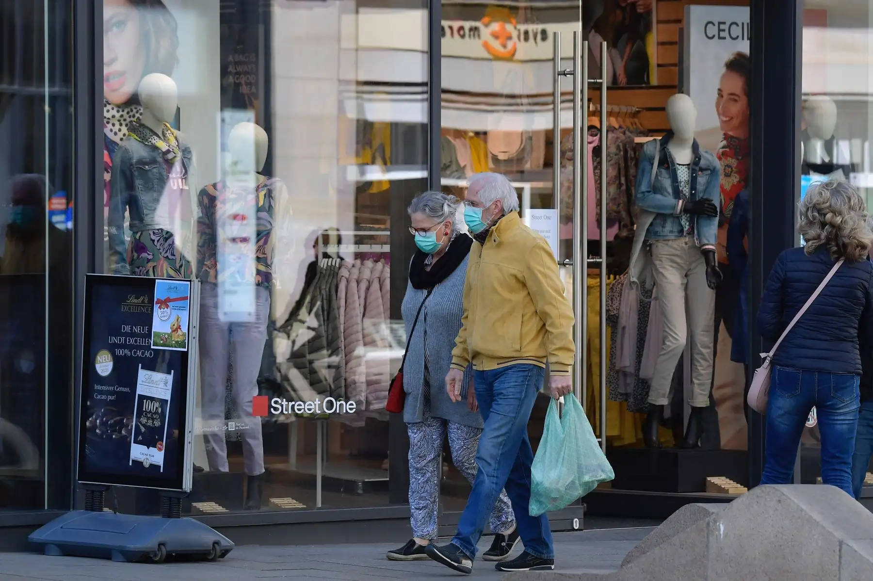 Una mujer y un hombre con máscaras faciales caminan frente a una tienda en Leipzig, Alemania oriental, el 20 de abril de 2020, en medio de la nueva pandemia de coronavirus COVID-19. Foto: AFP