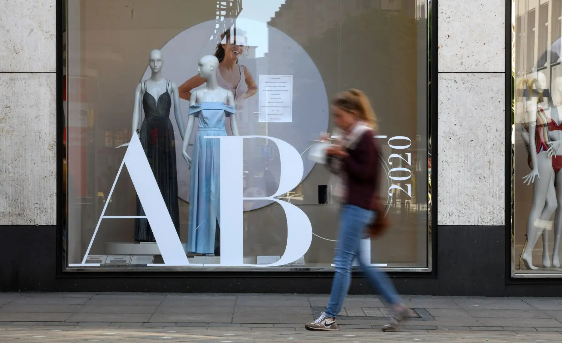 Una joven pasa por un escaparate con vestidos de noche de bachillerato en una calle peatonal de Dortmund, Alemania occidental, el 20 de abril de 2020, durante la nueva pandemia de coronavirus COVID-19. Foto: AFP