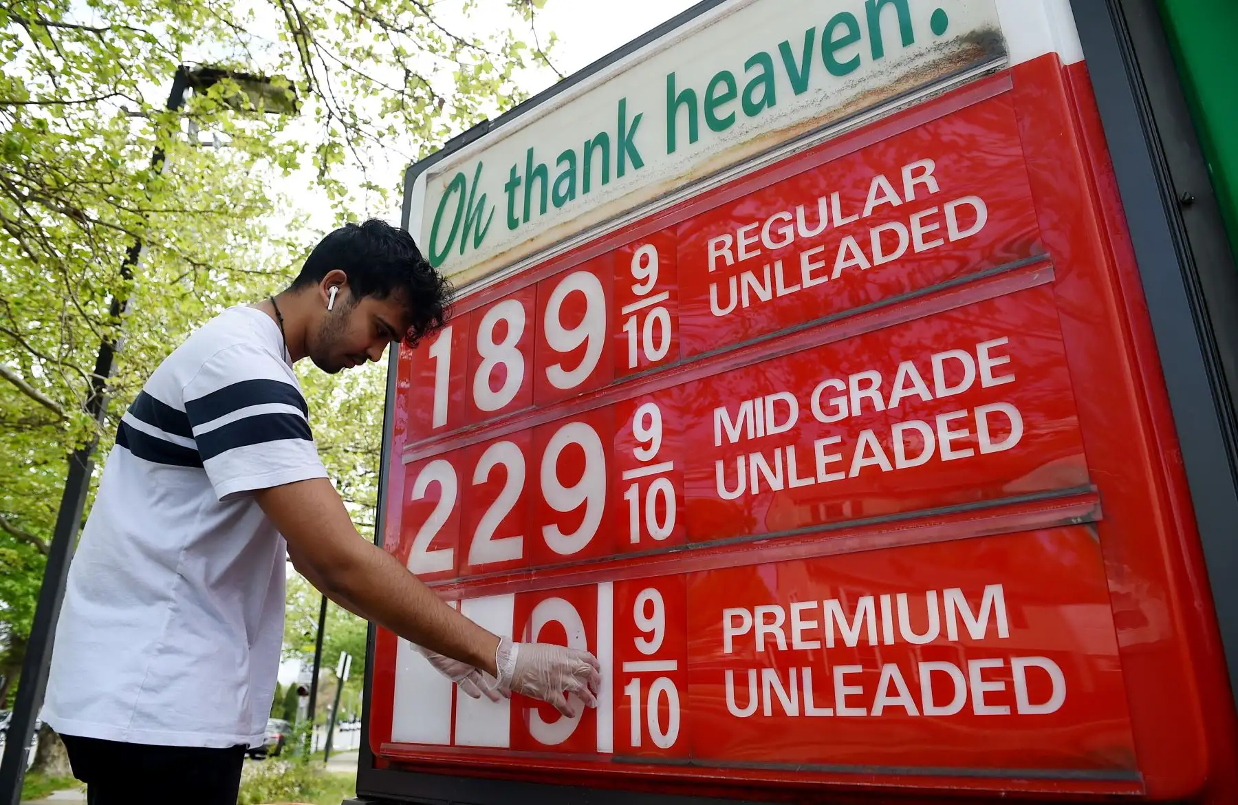 Un empleado de una estación de servicio en Virginia, Estados Unidos ajusta los precios de la gasolina a medida que continúan cayendo. Foto: AFP