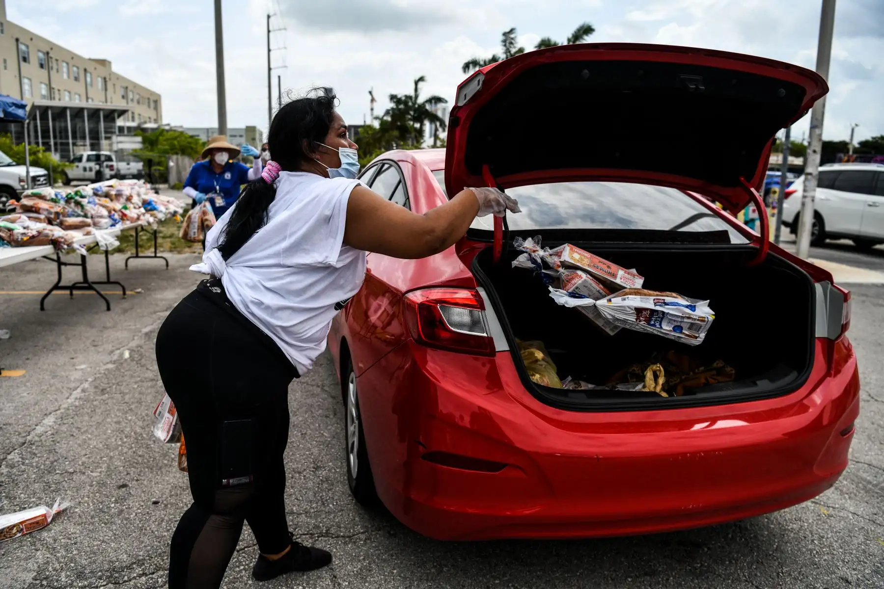 Una voluntaria distribuye paquetes de comestibles en un evento de distribución de alimentos organizado por Farm Share, Inc. en Miami. Foto: AFP