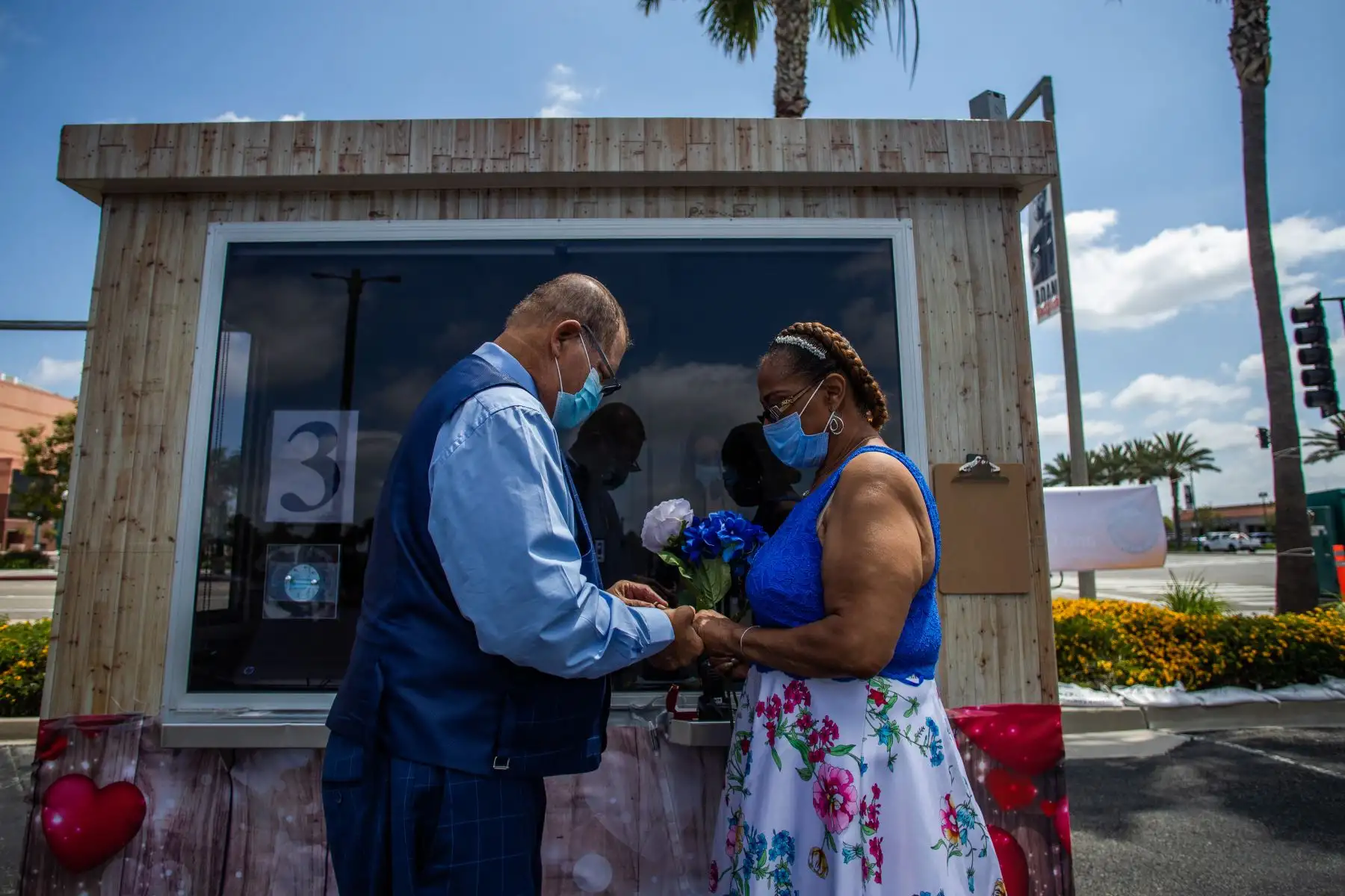 Michael Davis (izq.) Le pone el anillo a su novia Natasha durante su ceremonia de boda oficiada por un secretario de la oficina en el estacionamiento del Honda Center el 21 de abril de 2020 en Anaheim, California. Foto: AFP
