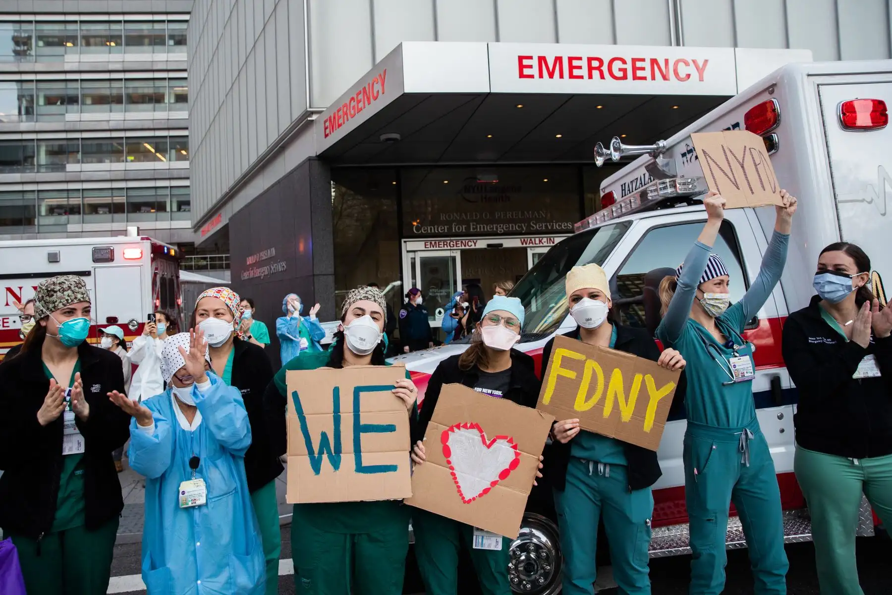 Trabajadores médicos sostienen carteles fuera del hospital Langone Health mientras la gente aplaude para mostrar su agradecimiento al personal médico y a los trabajadores esenciales en la primera línea de la pandemia de coronavirus. Foto: AFP