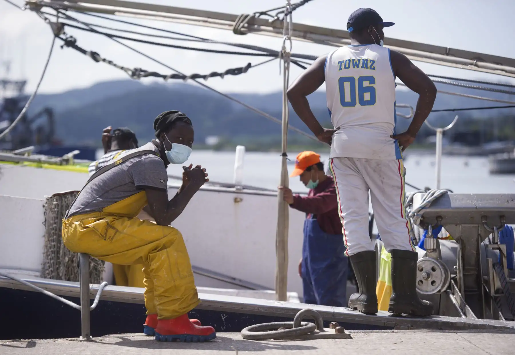 Los pescadores que usan equipo de protección, esperan descargar la captura del día de anchoas en el puerto de la ciudad española de Santona. Foto: AFP