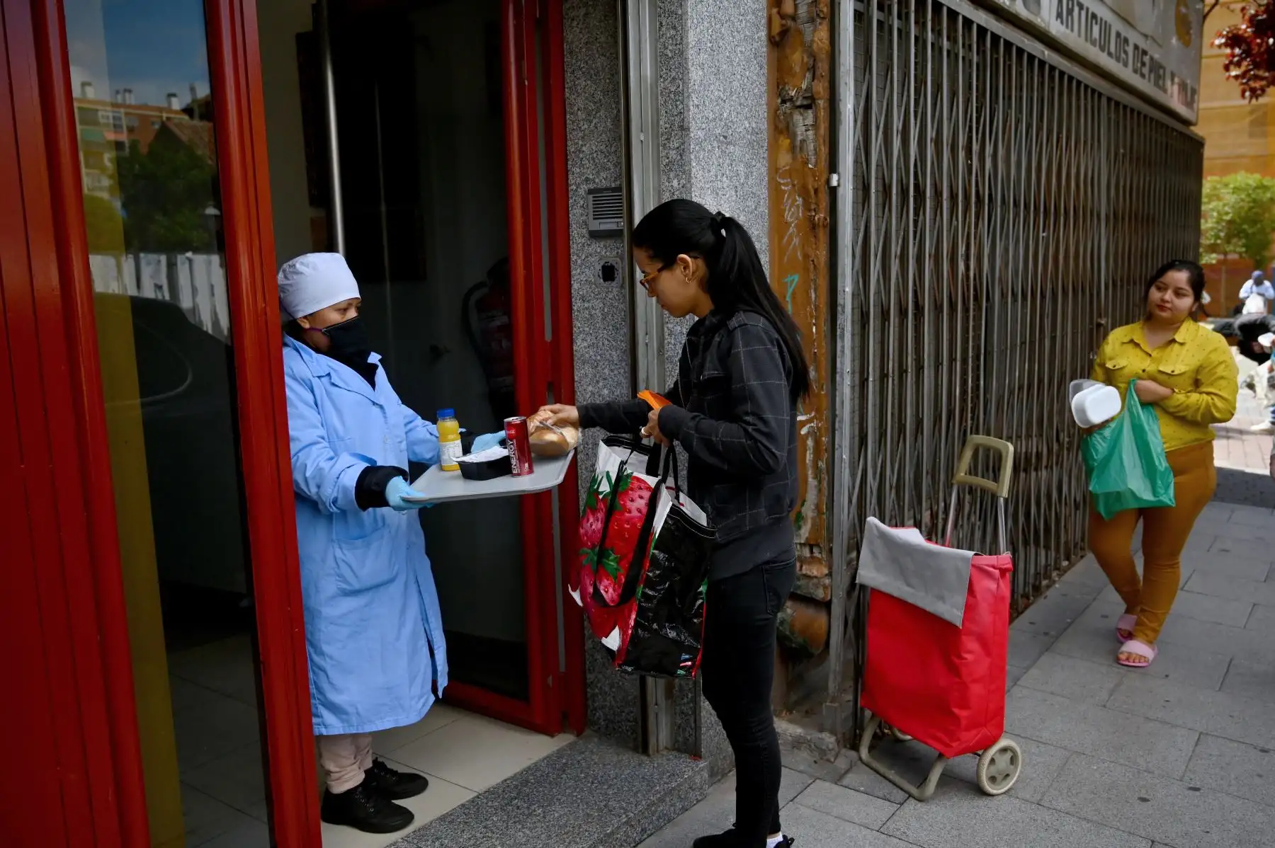 Una mujer necesitada recibe una ración de comida gratis en Puente de Vallecas, uno de los distritos más pobres de Madrid. Foto: AFP