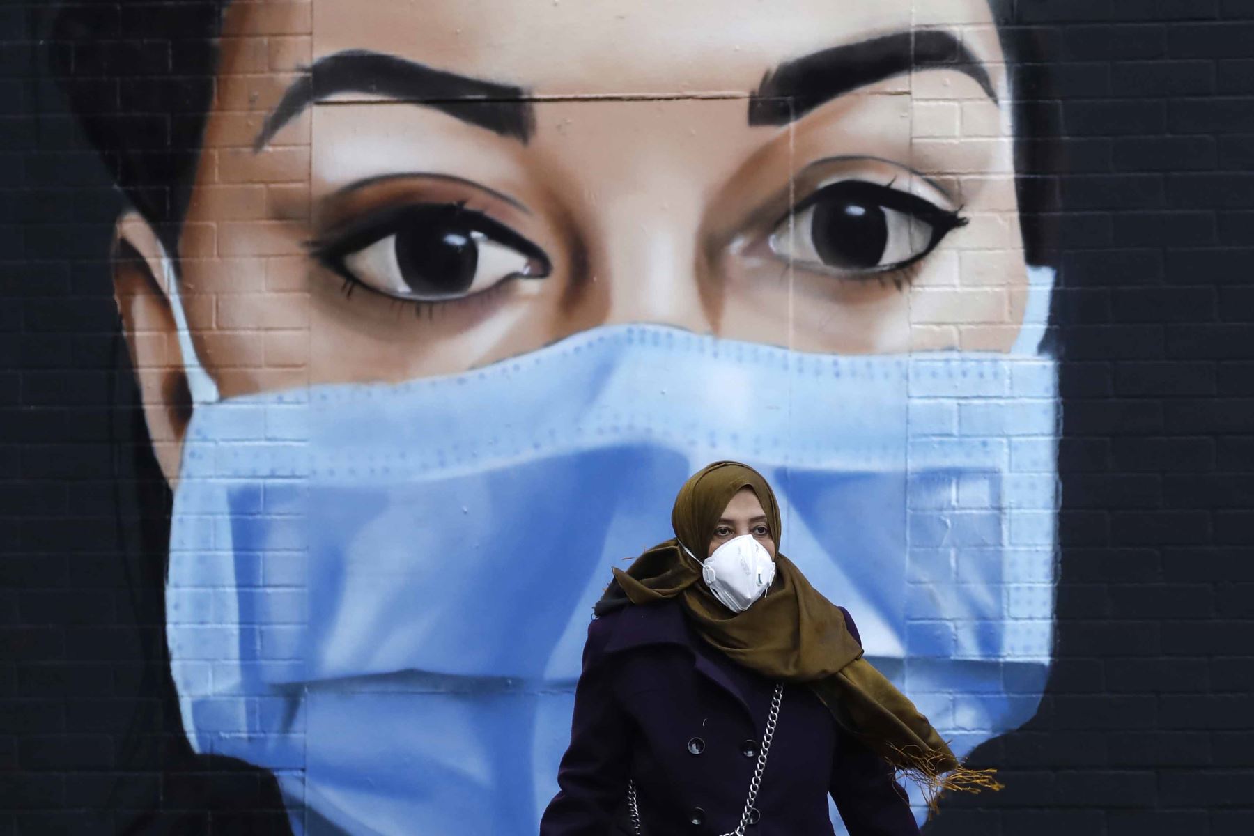 Las personas que usan PPE (equipo de protección personal) como medida de precaución contra COVID-19, pasan frente a un mural de un trabajador del NHS en el centro de Londres mientras Gran Bretaña permanece bajo llave durante la crisis del coronavirus. Foto: AFP