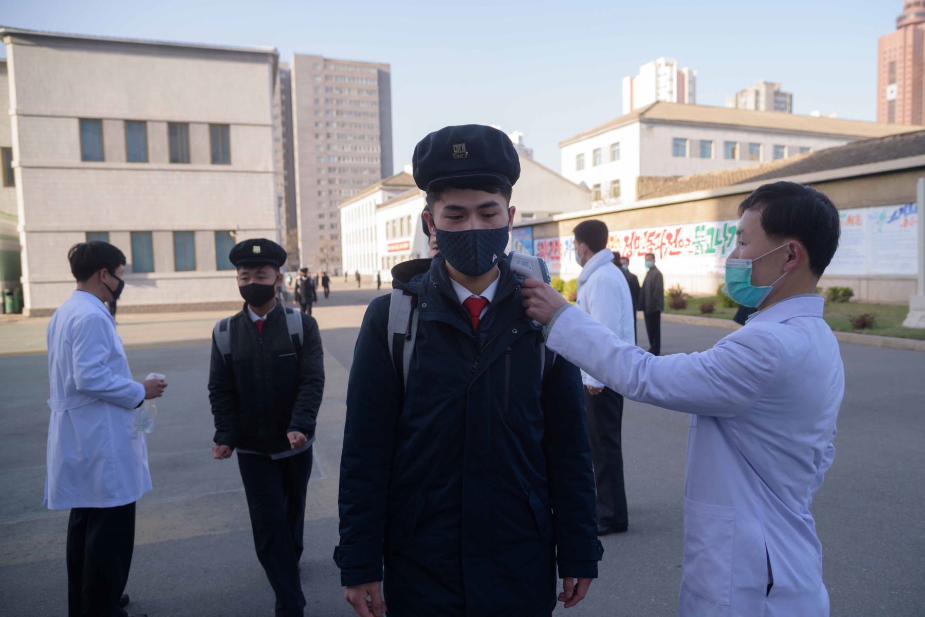 Los estudiantes que usan mascarillas desinfectan sus manos y se someten a un control de temperatura cuando llegan a una conferencia sobre medidas preventivas contra el nuevo coronavirus COVID-19 en la Universidad de Medicina de Pyongyang. Foto: AFP