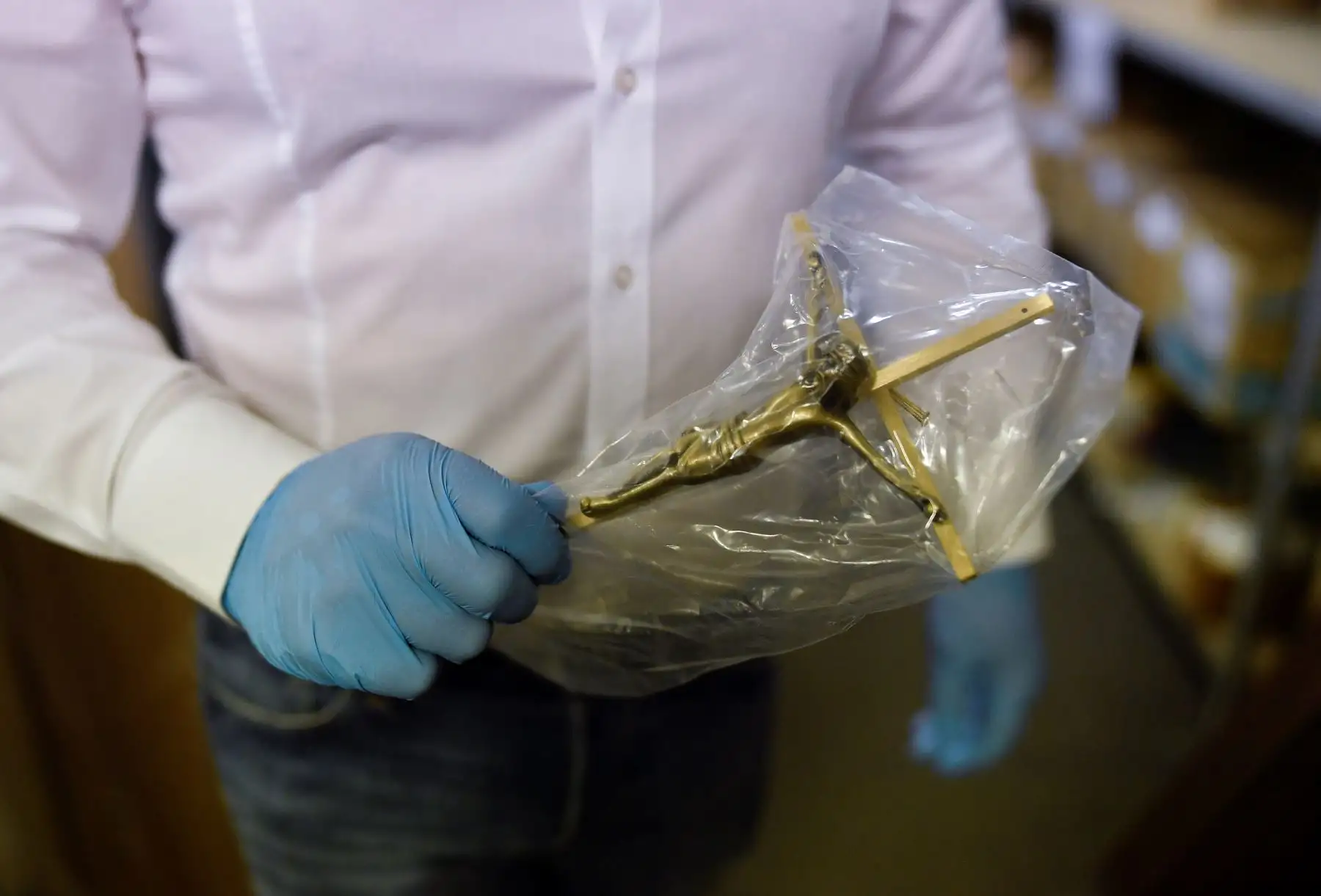 Un empleado de la funeraria Chaudoir con guantes sostiene una cruz cristiana antes de instalarla en el ataúd de una persona que murió del COVID-19. Foto: AFP