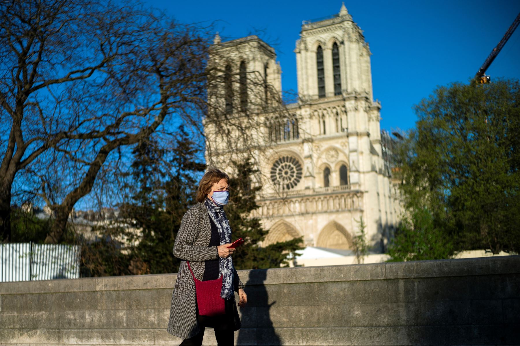 Una mujer con una máscara facial protectora camina frente a la catedral de Notre-Dame en París, Francia. Foto: EFE