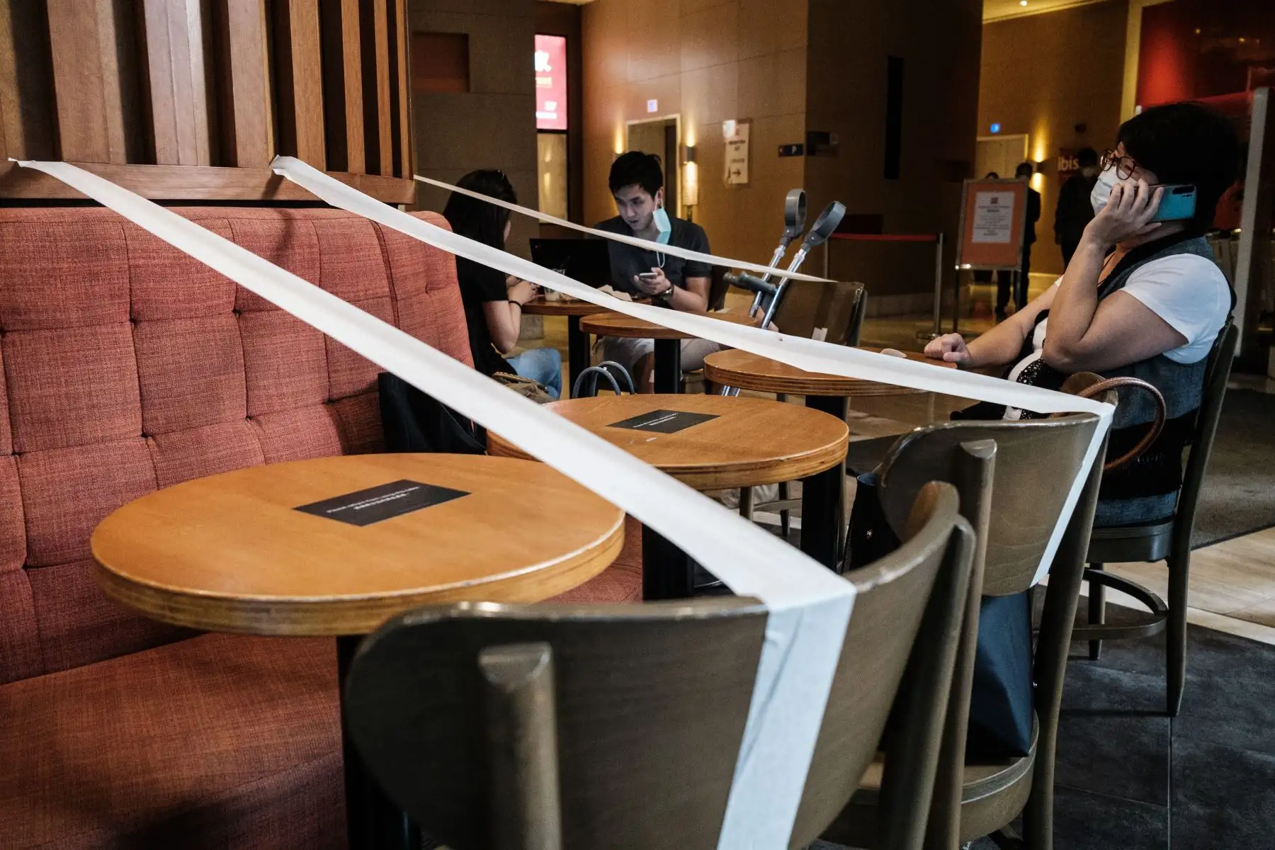 Los clientes que usan mascarillas como medida de precaución contra el coronavirus COVID-19 se sientan en un café, que tiene cintas adhesiva en todas las mesas para reforzar el distanciamiento social en Hong Kong. Foto: AFP
